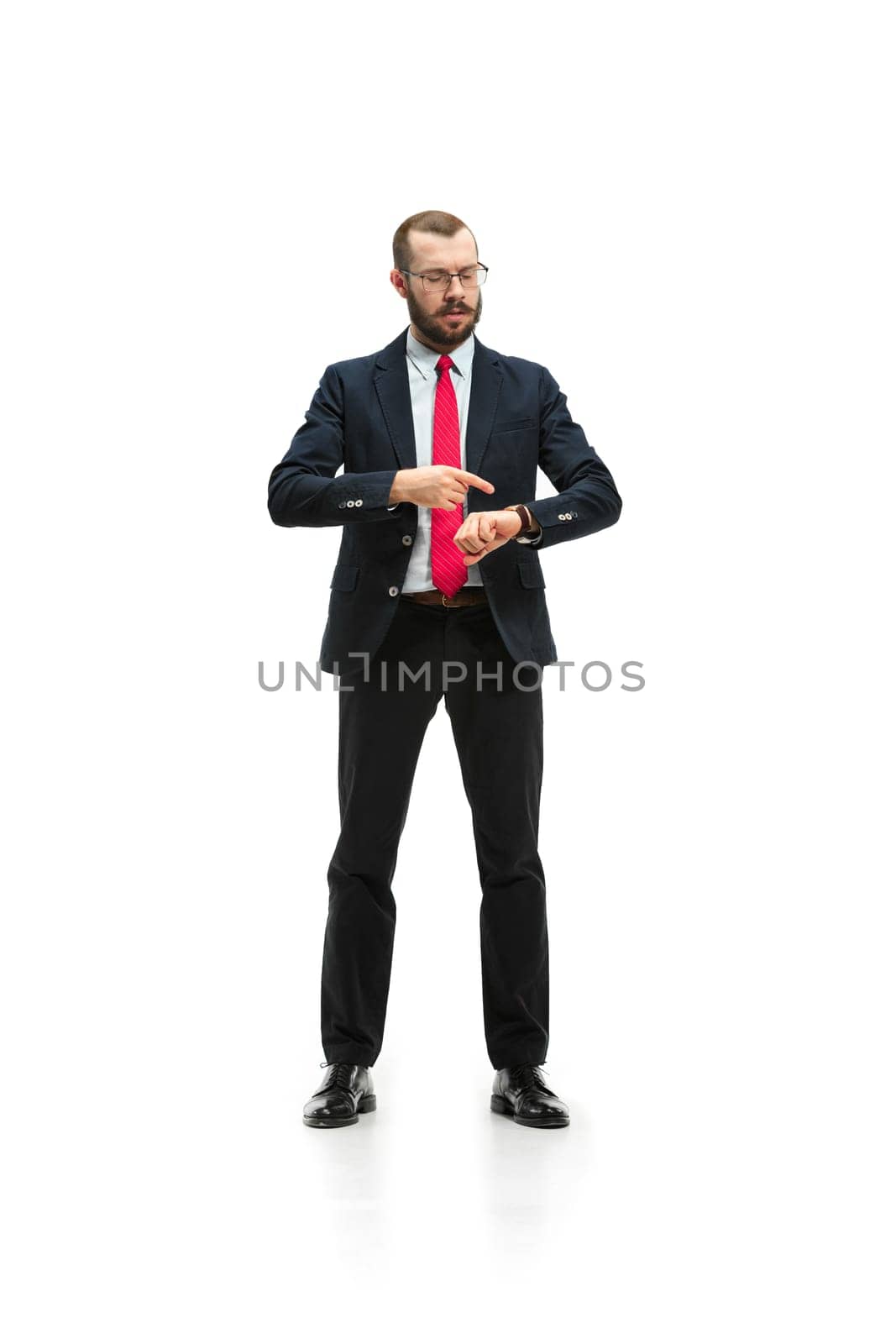 Businessman looking at his watch on his hand, watching the time. portrait of businessman on white studio background. Serious bearded young man in glasses, suit, red tie standing in office. Business concept.