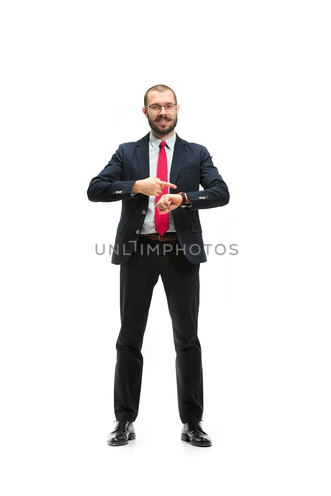 Businessman looking at his watch on his hand, watching the time. portrait of businessman on white studio background. Serious bearded young man in glasses, suit, red tie standing in office. Business concept.