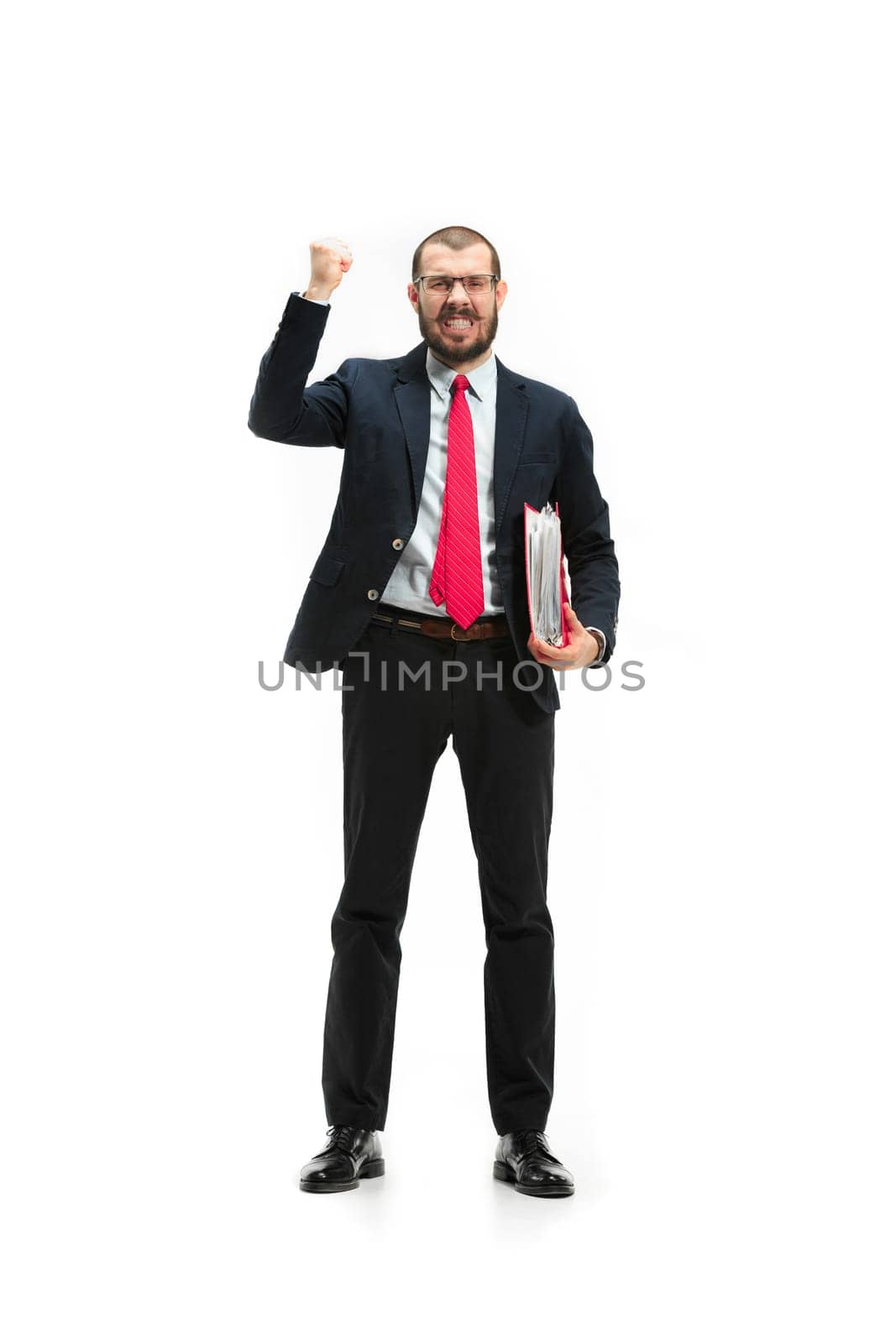 Full body or full-length portrait of businessman with red folder on white studio background. Happy bearded young man in glasses, suit, red tie standing in office. Business, career, success concept.