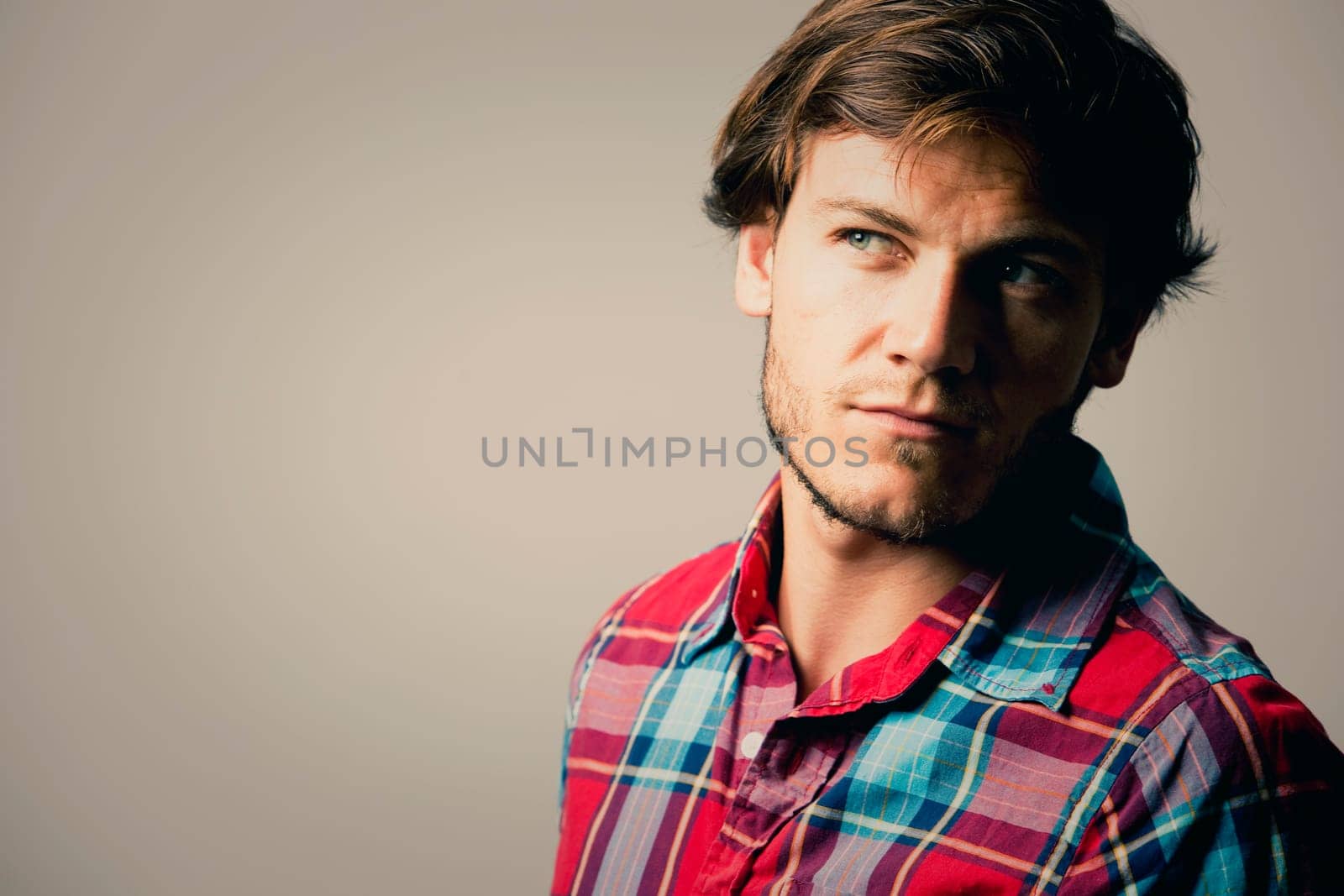 Fashion portrait of a handsome man with trendy hairstyle in a stylish shirt on light green background