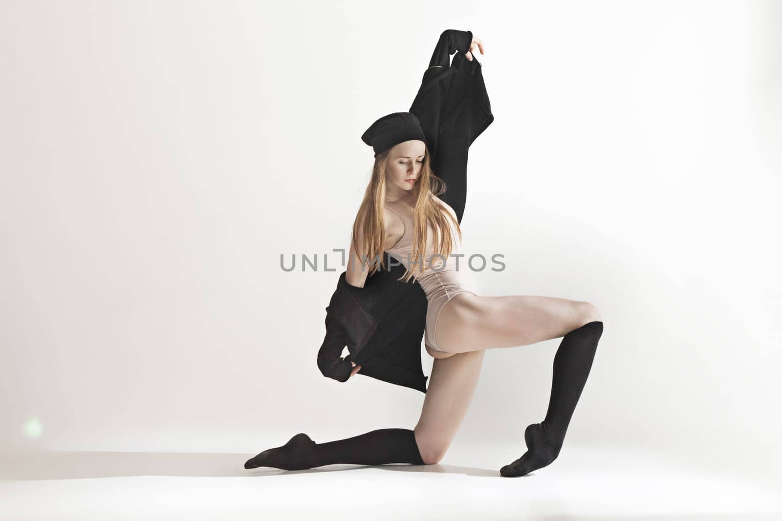 Young beautiful dancer in beige swimsuit dancing on gray studio background. Front view. Young female classical ballet dancer. Ballerina project. Modern choreography, contemporary. Fit caucasian moman