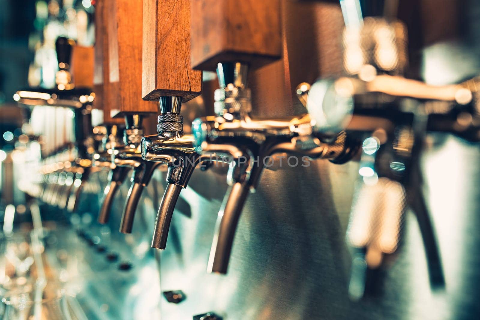 The beer taps in a pub. nobody. Selective focus. Alcohol concept. Vintage style. Beer craft. Bar table. Steel taps. Shiny taps. Glass of beer