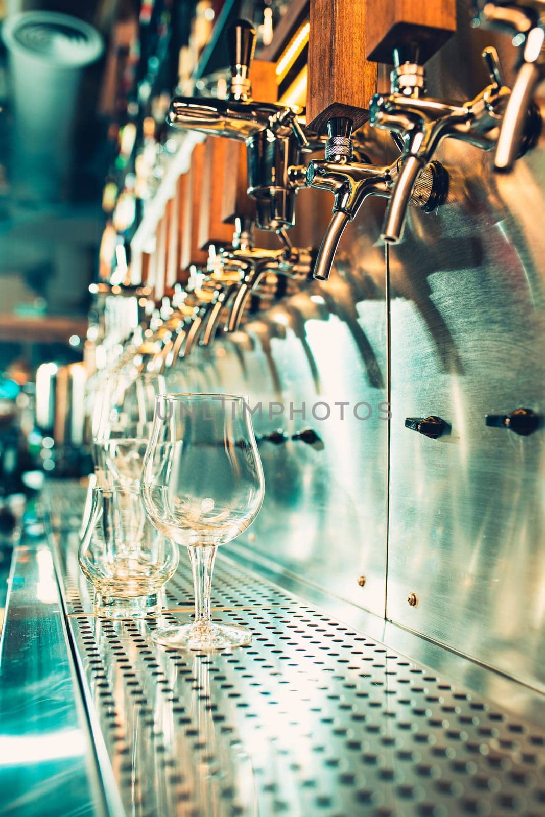The beer taps in a pub. nobody. Selective focus. Alcohol concept. Vintage style. Beer craft. Bar table. Steel taps. Shiny taps. Glass of beer