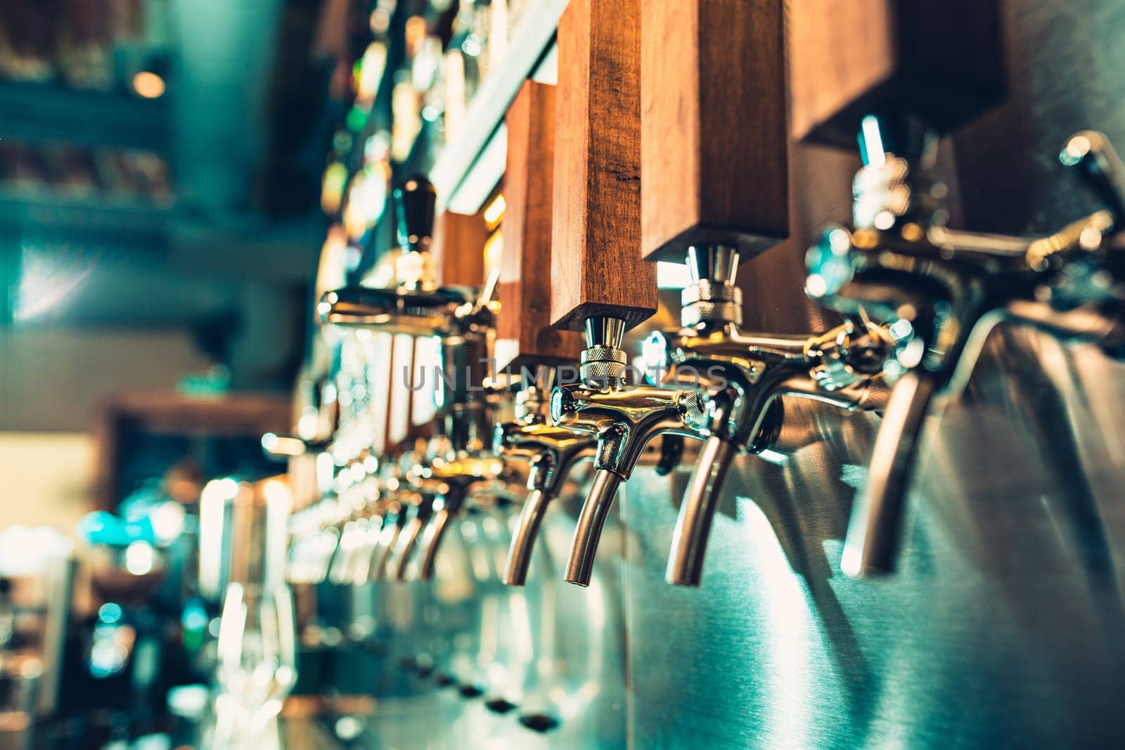The beer taps in a pub. nobody. Selective focus. Alcohol concept. Vintage style. Beer craft. Bar table. Steel taps. Shiny taps. Glass of beer