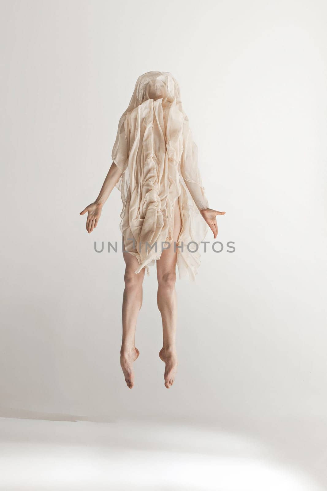 Young beautiful dancer in beige swimsuit dancing on gray studio background. Front view. Young female classical ballet dancer. Ballerina project. Modern choreography, contemporary. Fit caucasian moman