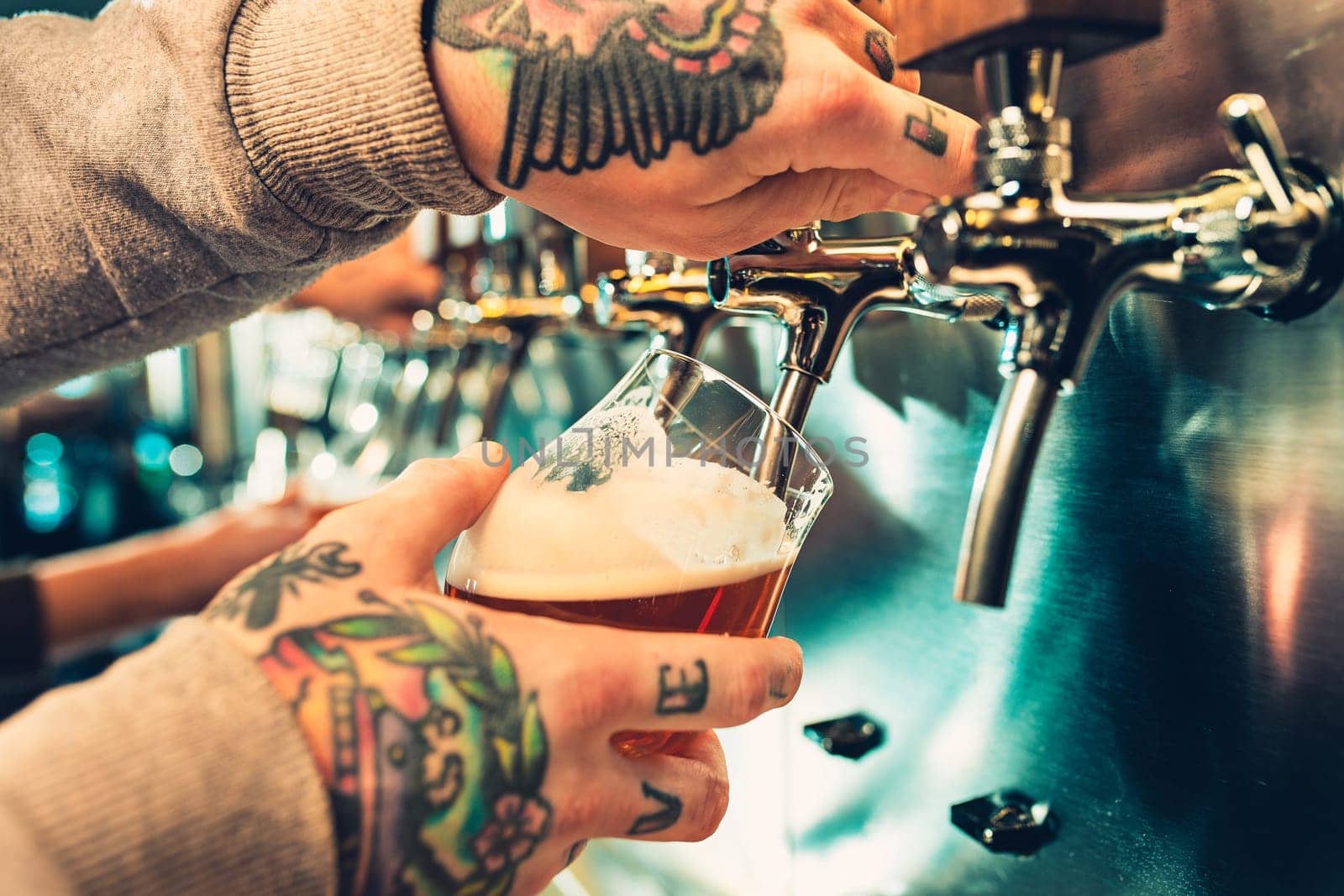 Hand of bartender pouring a large lager beer in tap. Soft, vintage instagram effect on photo. Pouring beer for client. Side view of young bartender pouring beer while standing at the bar counter