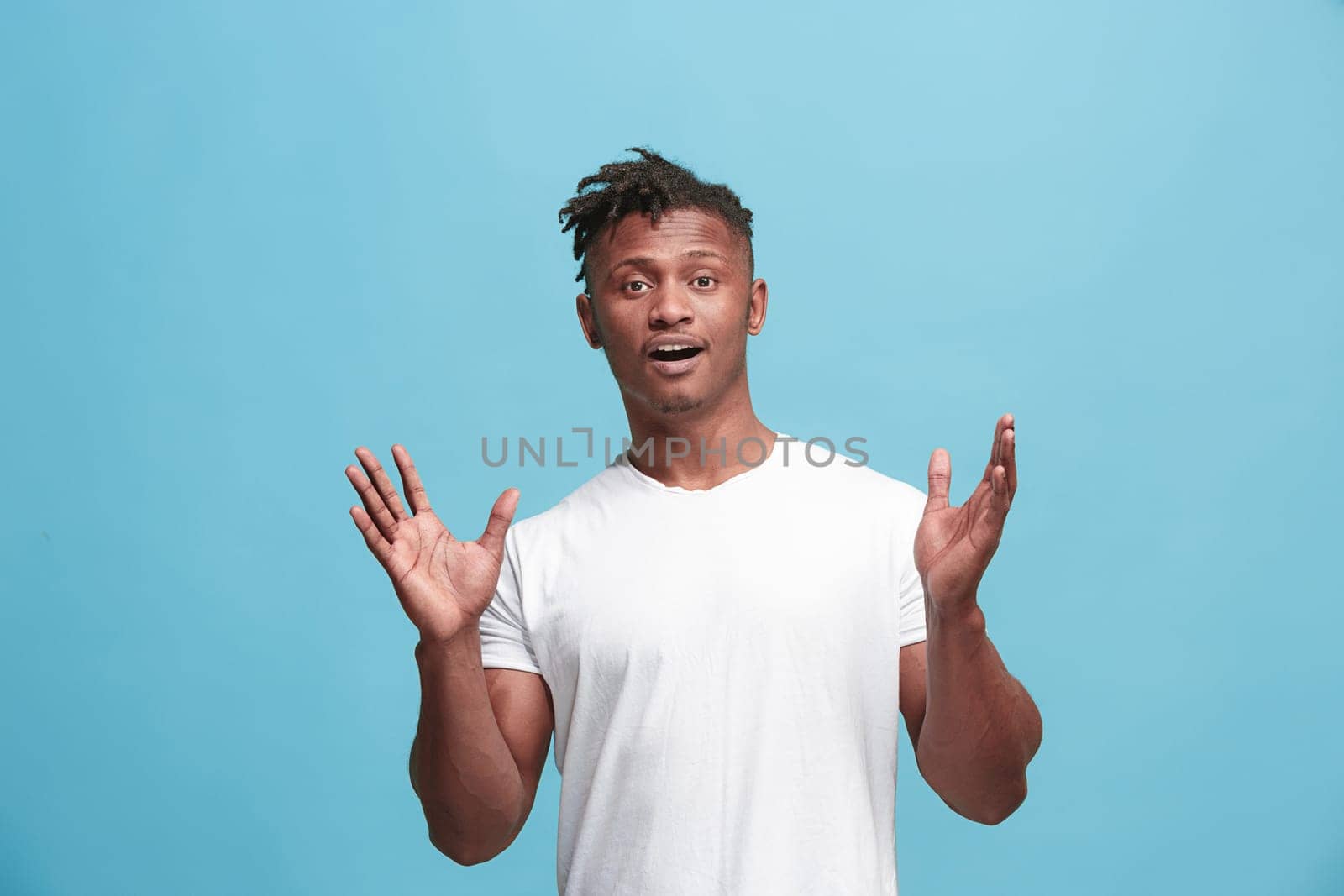 Delight. African american male half-length front portrait isolated on blue studio backgroud. Young, emotional, smiling, surprised man standing. Human emotions, facial expression concept. Trendy colors