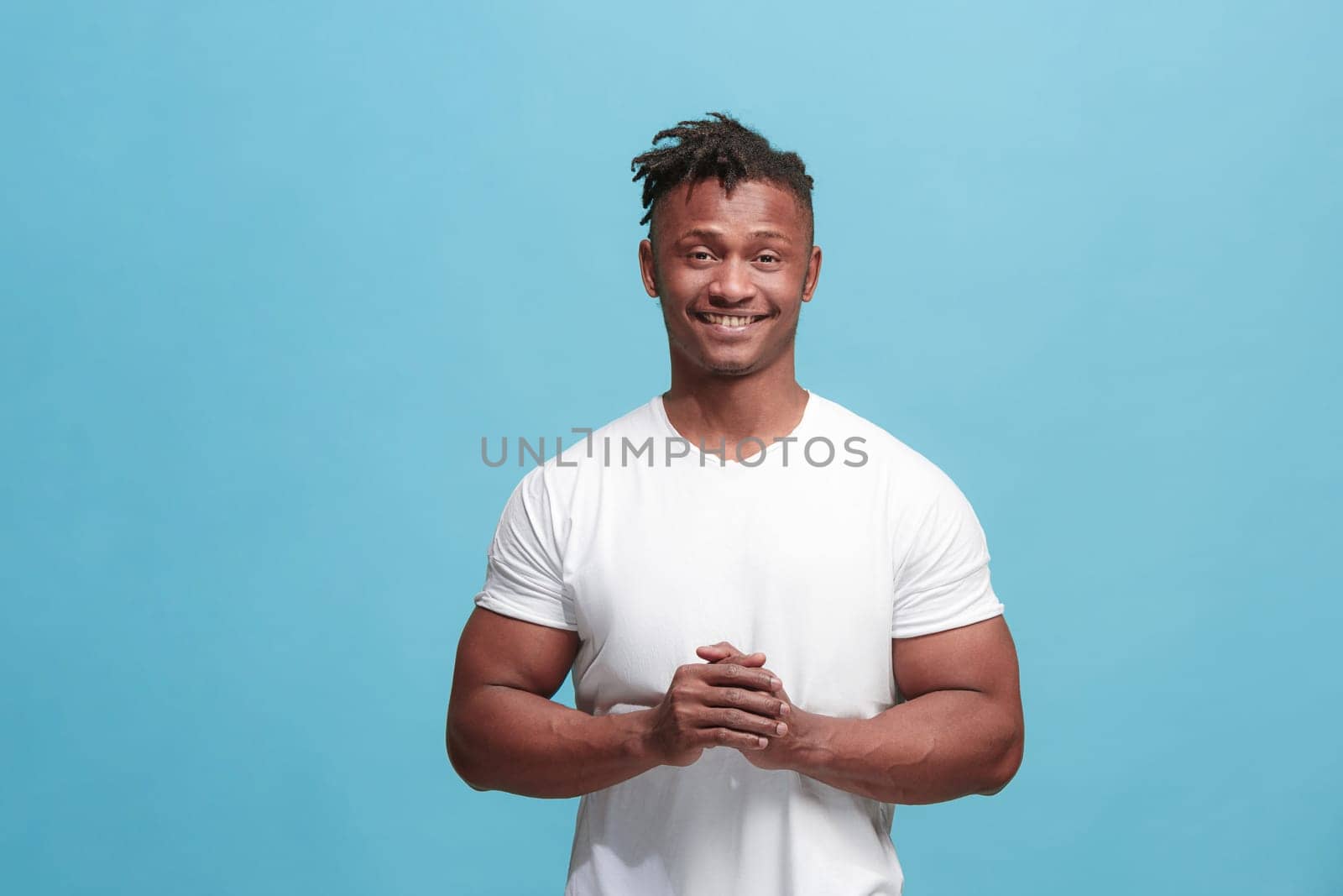 Happy business man standing and smiling isolated on blue studio background. African American male half-length portrait. Young emotional man. The human emotions, facial expression concept. Front view.
