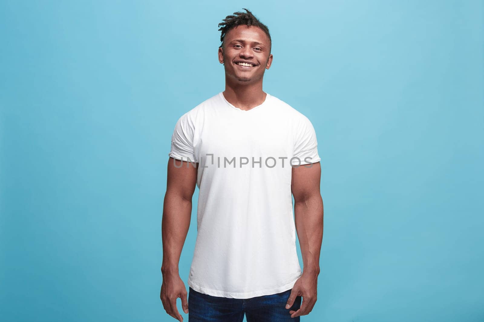 Happy business man standing and smiling isolated on blue studio background. African American male half-length portrait. Young emotional man. The human emotions, facial expression concept. Front view.