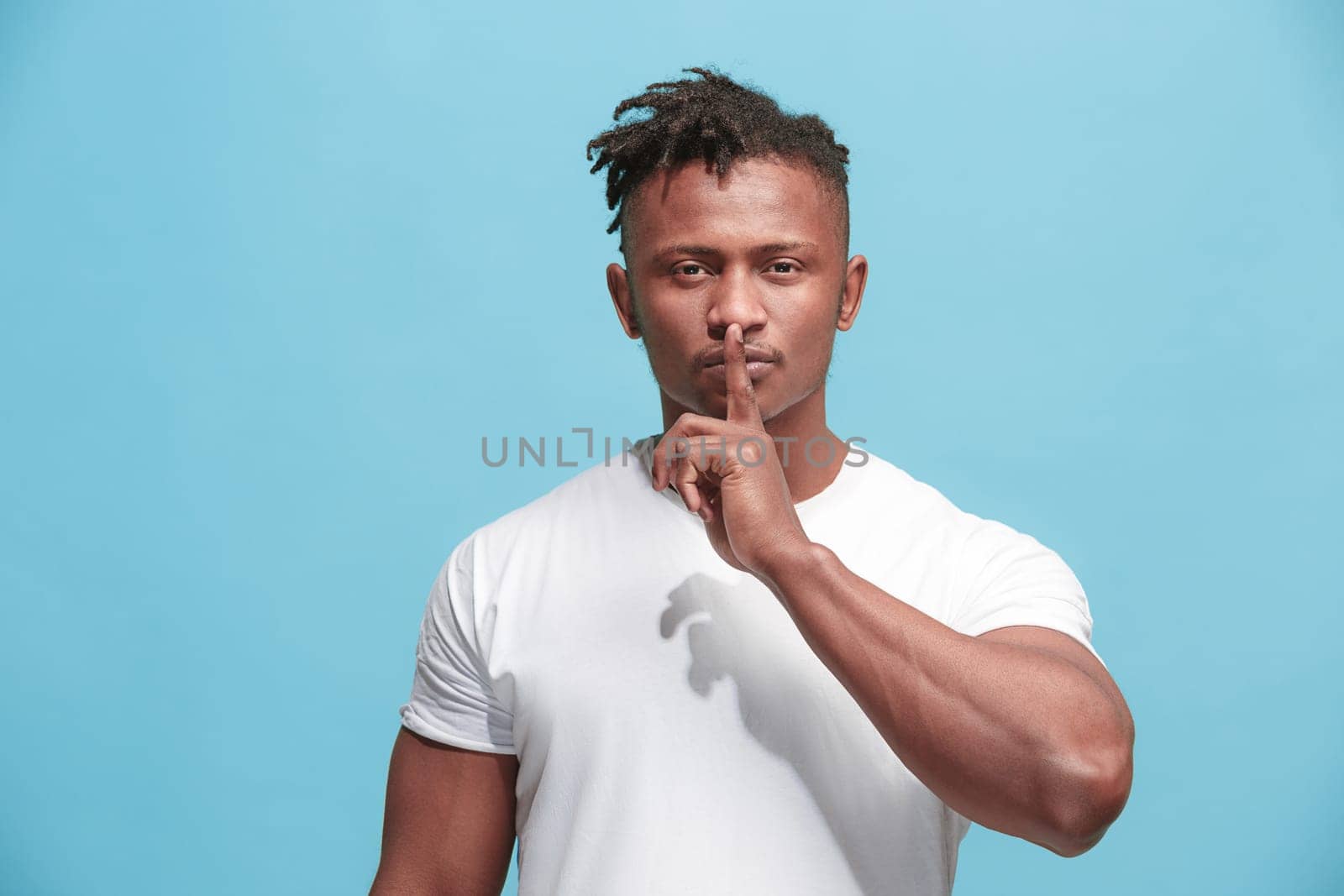 Secret, gossip concept. Young man whispering a secret behind his hand. Businessman isolated on trendy blue studio background. Young emotional man. Human emotions, facial expression concept. afro-american