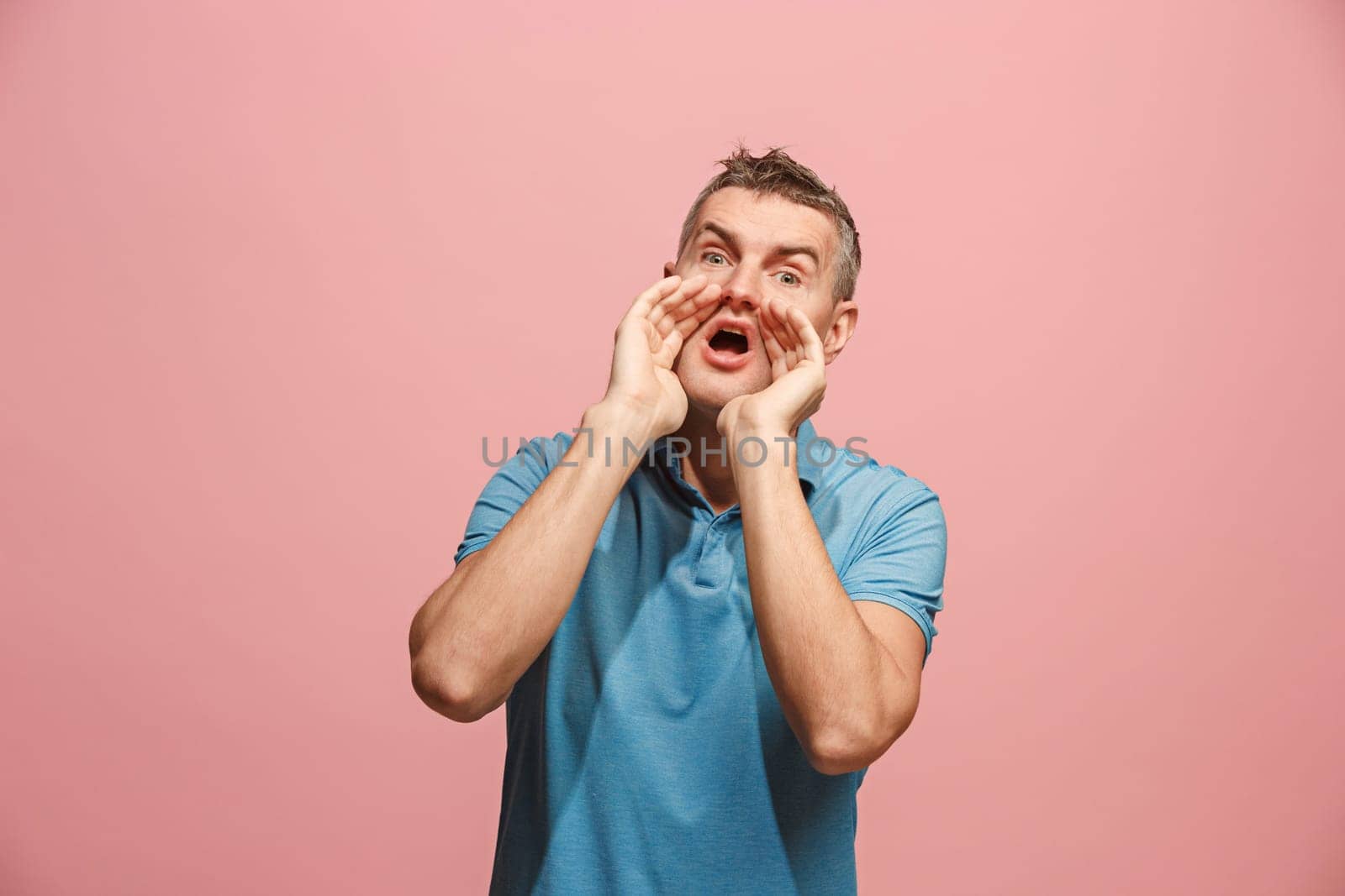 Do not miss. Young casual man shouting. Shout. Crying emotional man screaming on pink studio background. male half-length portrait. Human emotions, facial expression concept. Trendy colors