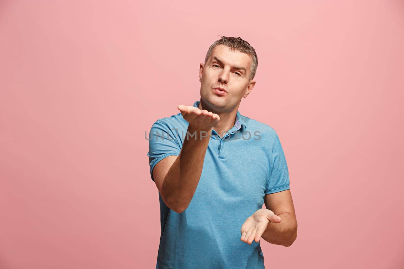 I kiss you. Portrait of attractive man with kiss on lips. Pink studio. Beautiful male portrait. Young happy emotional funny man looking at camera. Human facial emotions concept. Trendy colors