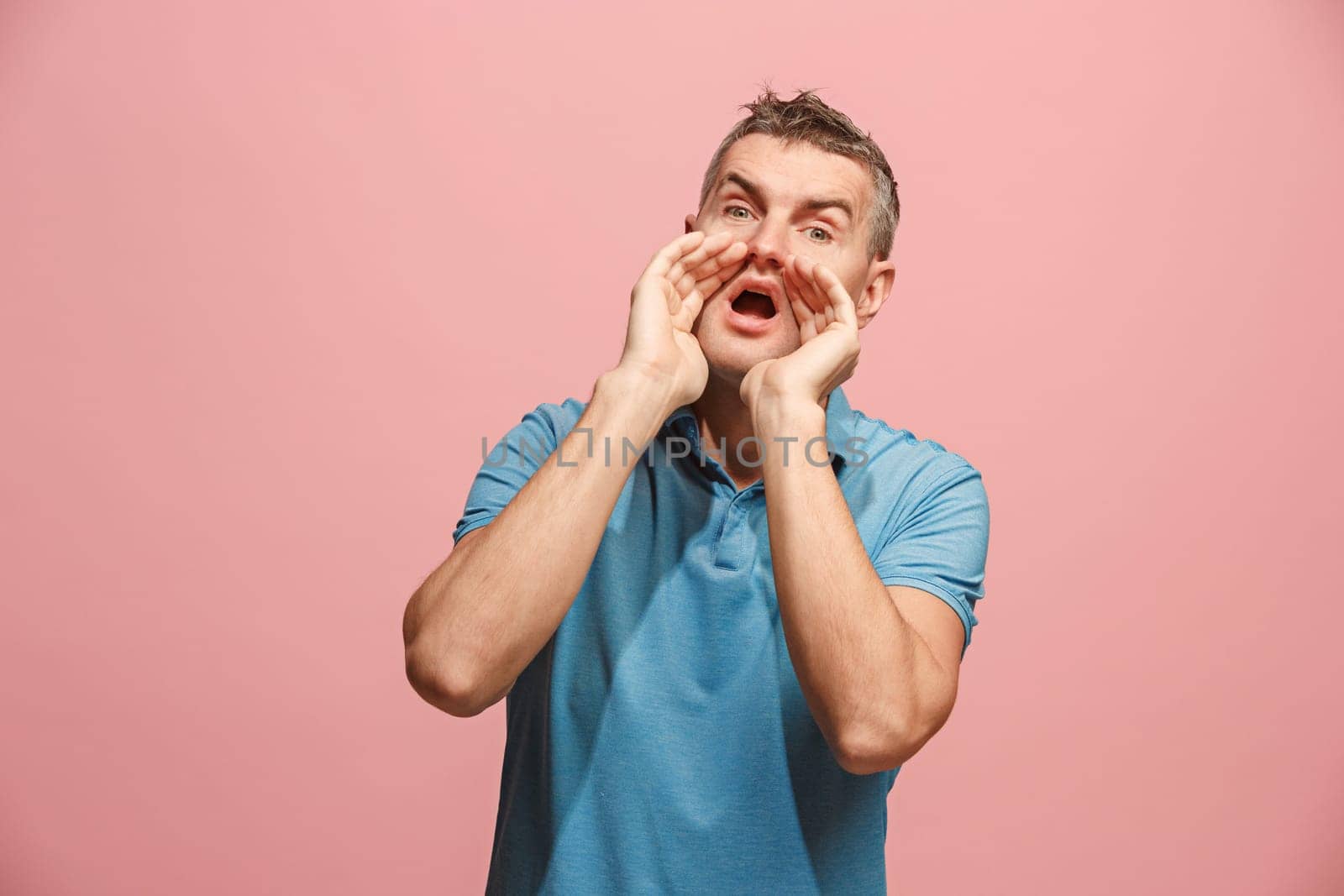 Do not miss. Young casual man shouting. Shout. Crying emotional man screaming on pink studio background. male half-length portrait. Human emotions, facial expression concept. Trendy colors