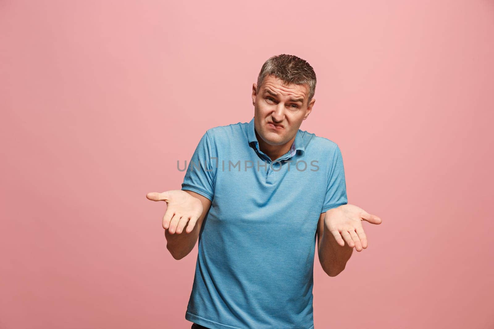 Argue, arguing concept. Beautiful male half-length portrait isolated on pink studio backgroud. Young emotional surprised man looking at camera. Human emotions, facial expression concept. Front view
