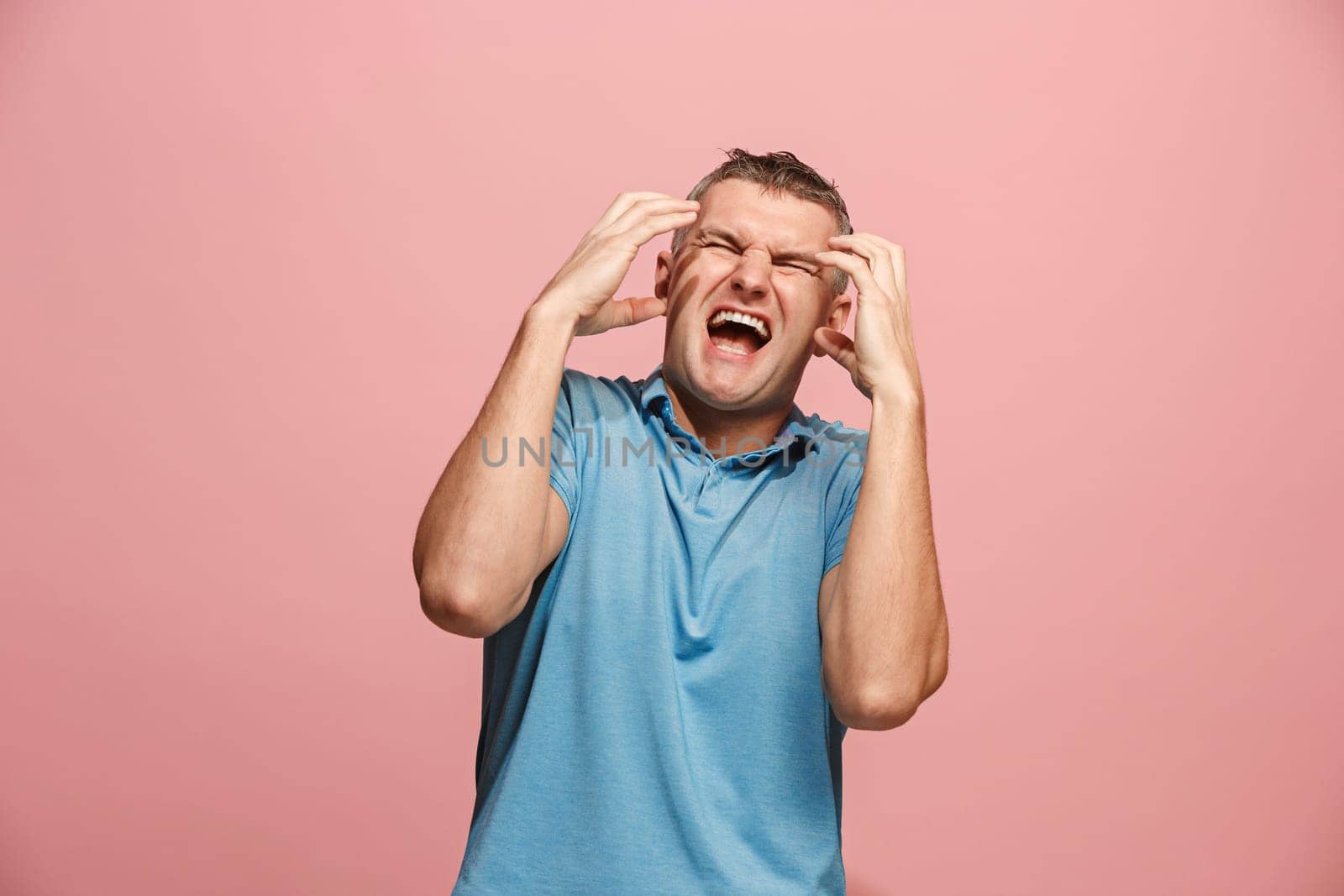 Screaming, hate, rage. Crying emotional angry man screaming on pink studio background. Emotional, young face. male half-length portrait. Human emotions, facial expression concept. Trendy colors