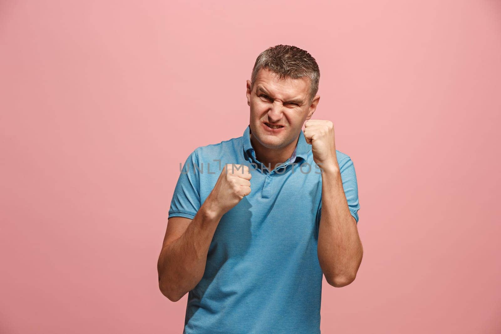 Screaming, hate, rage. Crying emotional angry man screaming on pink studio background. Emotional, young face. male half-length portrait. Human emotions, facial expression concept. Trendy colors