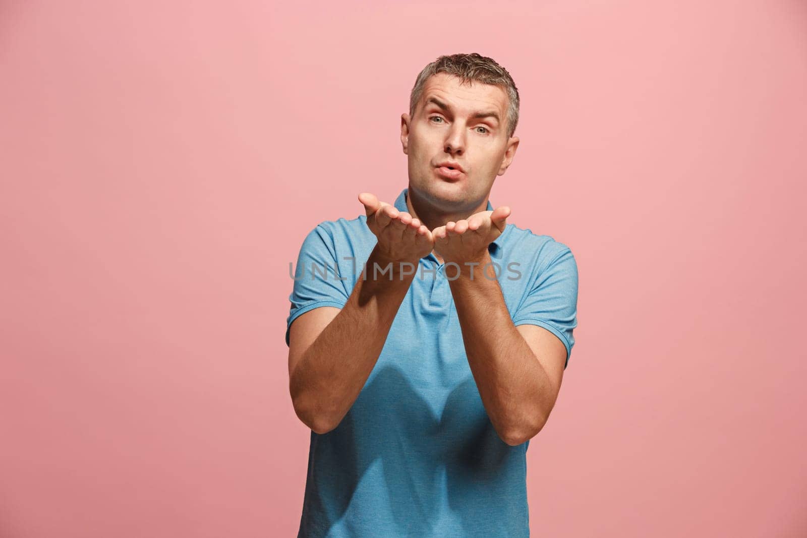 I kiss you. Portrait of attractive man with kiss on lips. Pink studio. Beautiful male portrait. Young happy emotional funny man looking at camera. Human facial emotions concept. Trendy colors