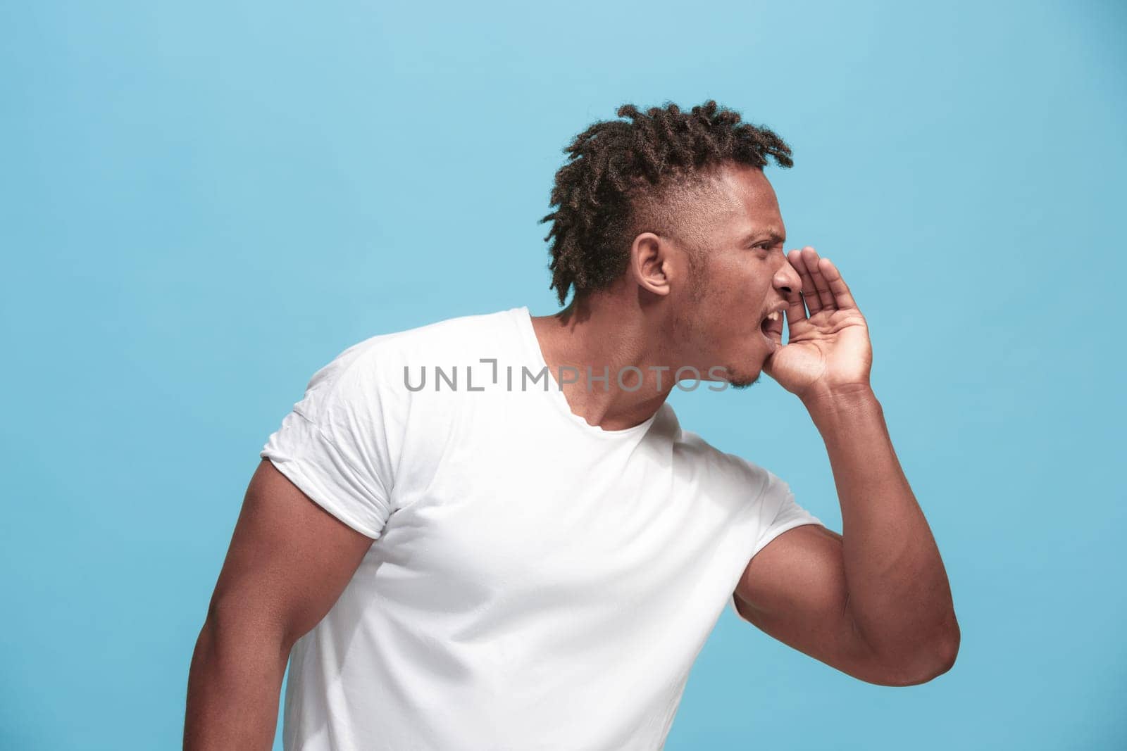 Secret, gossip concept. Young man whispering a secret behind his hand. Businessman isolated on trendy blue studio background. Young emotional man. Human emotions, facial expression concept. afro-american. profile