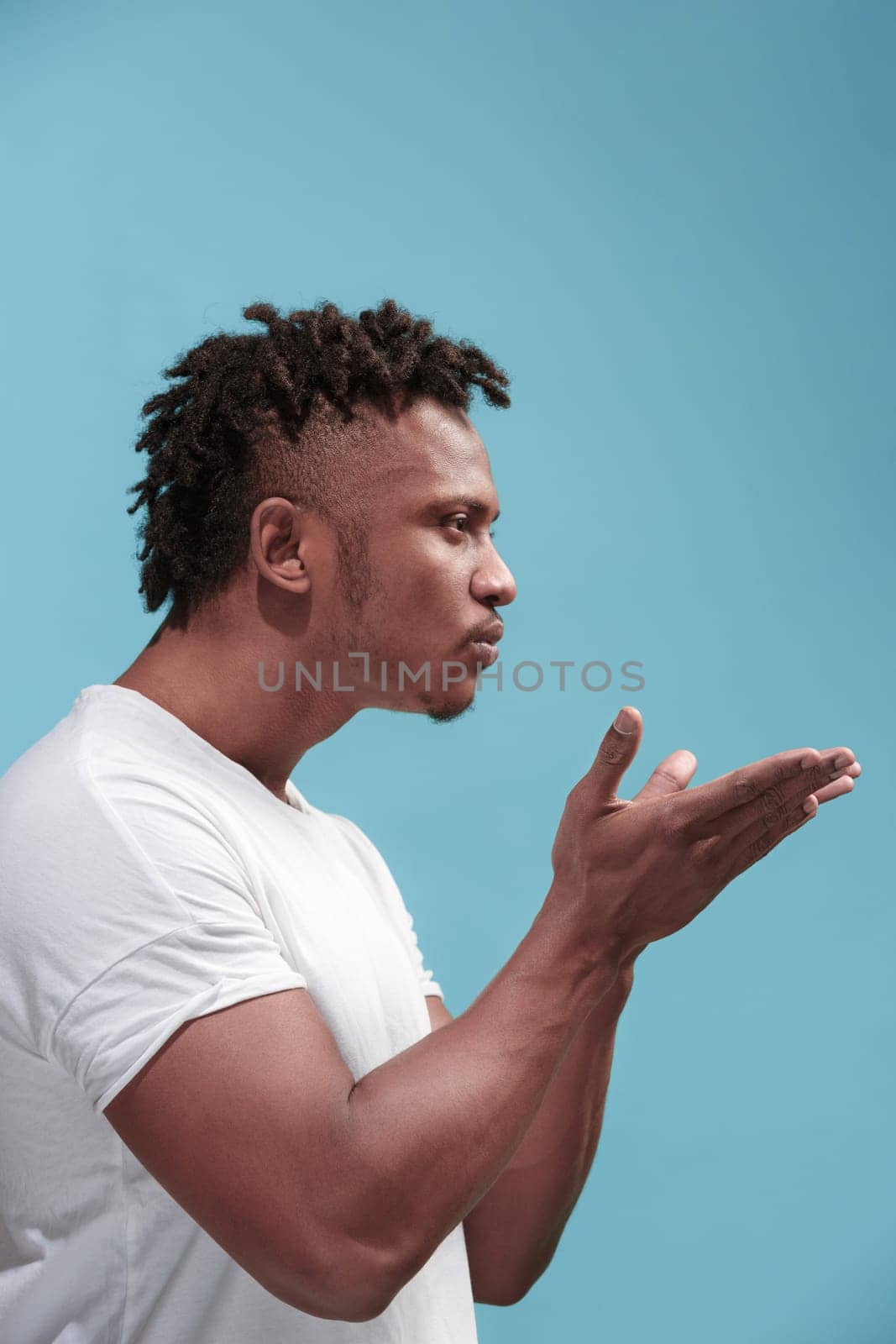 I kiss you. Profile portrait of attractive afro man with air kiss on lips. Blue studio. Beautiful male portrait. Young happy emotional funny man . Human facial emotions concept. Trendy colors