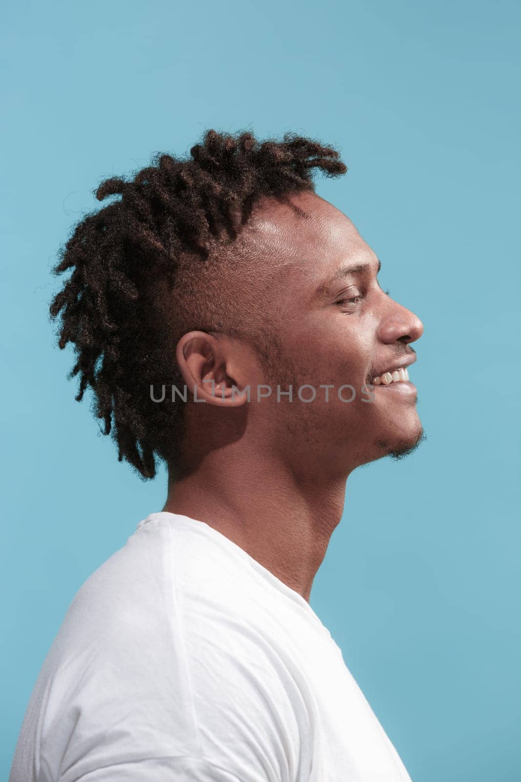 Happy business Afro-American man standing and smiling isolated on blue studio background. African American male profile portrait. Young emotional man. The human emotions, facial expression concept.