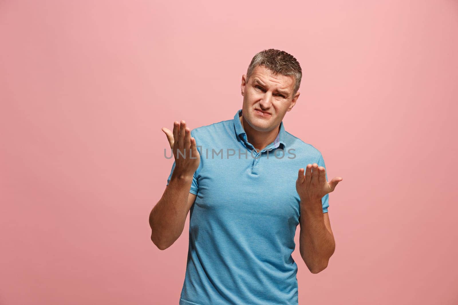 Argue, arguing concept. Beautiful male half-length portrait isolated on pink studio backgroud. Young emotional surprised man looking at camera. Human emotions, facial expression concept. Front view