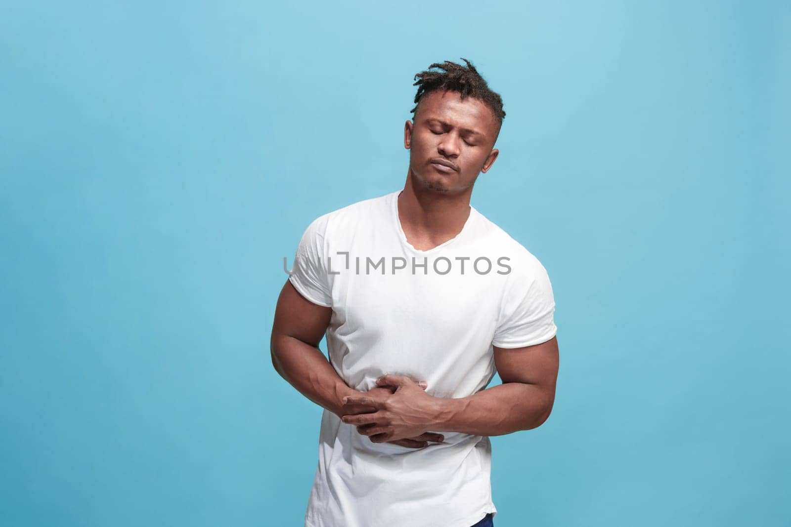 Pain concept. Beautiful male portrait isolated on blue backgroud. Young emotional surprised man looking at camera.Human emotions, facial expression concept. man overwhelmed with pain in stomach