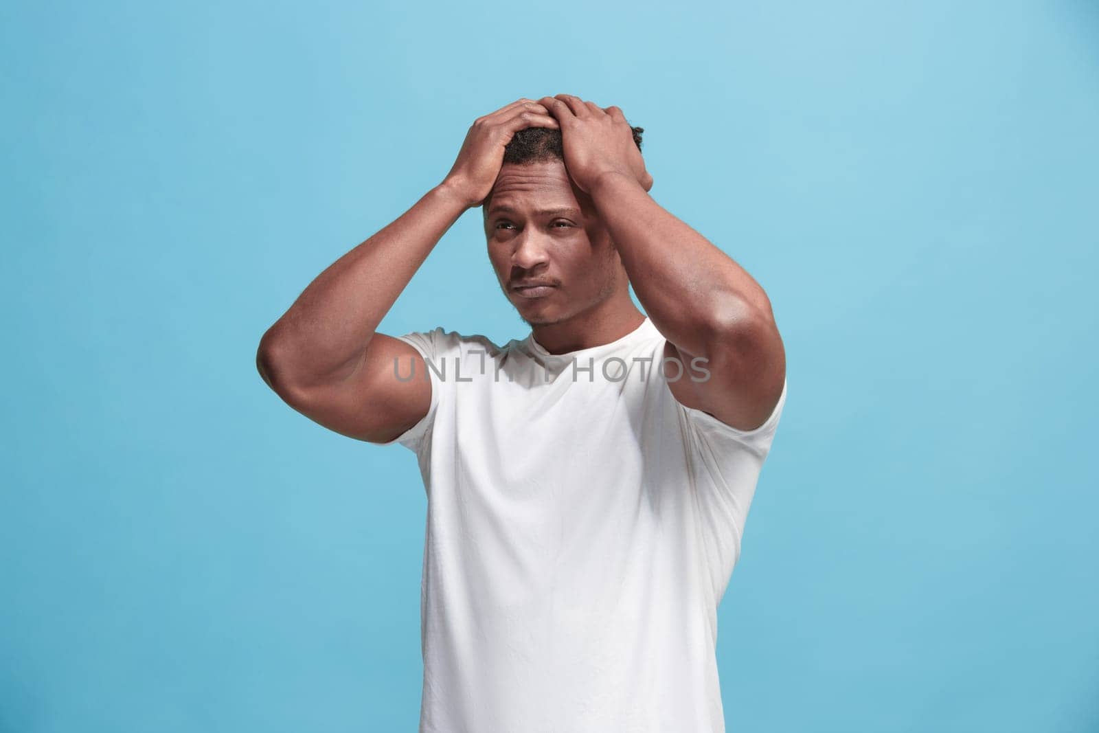Afro Man having headache. Isolated on blue background. Business man standing with pain isolated on trendy pink studio background. Male half-length portrait. Human emotions, facial expression concept. Front
