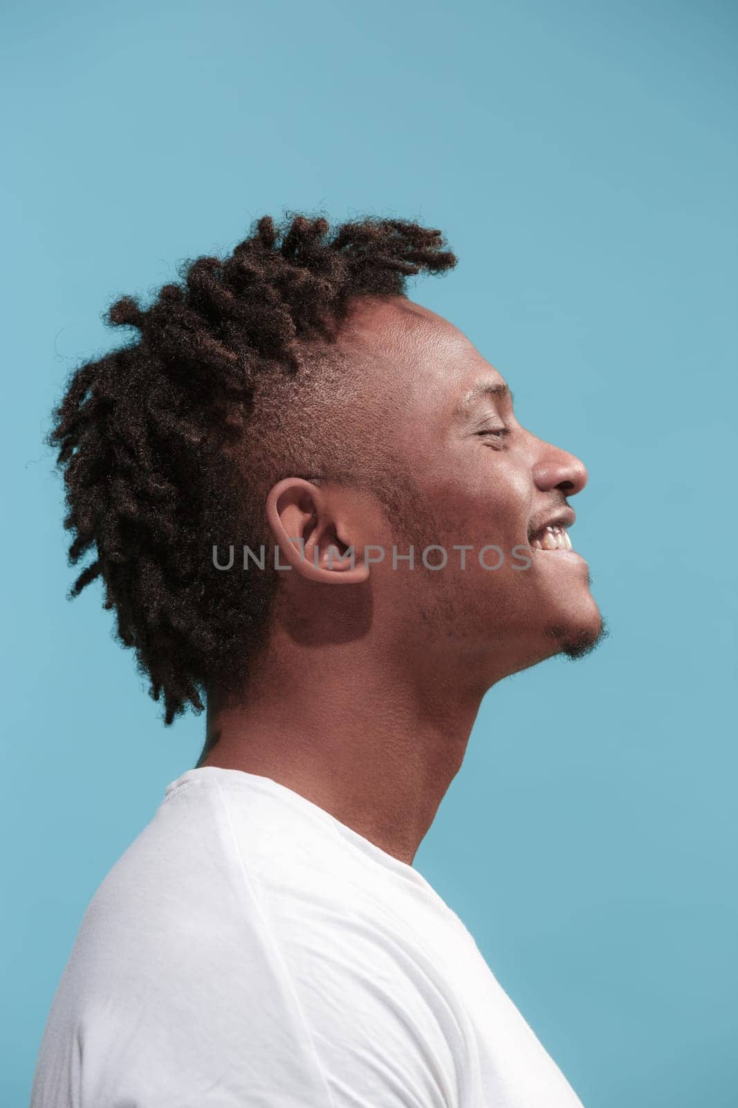 Happy business Afro-American man standing and smiling isolated on blue studio background. African American male profile portrait. Young emotional man. The human emotions, facial expression concept.