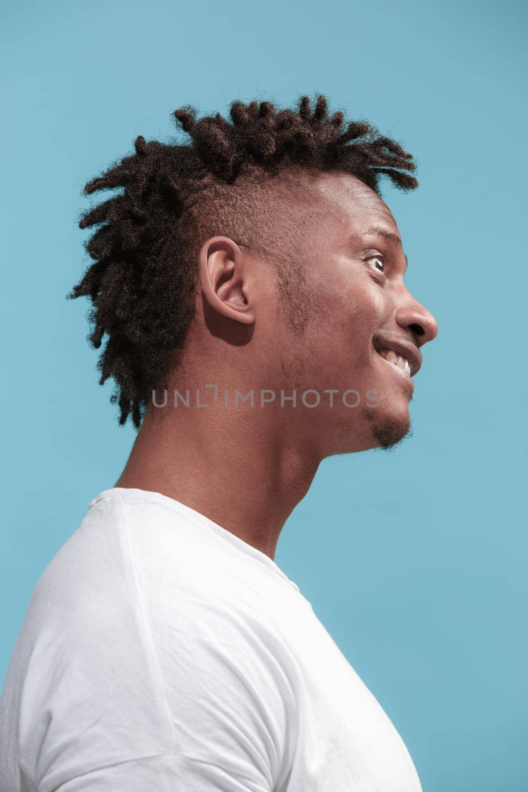 Crazy business Afro-American man standing and wrinkle face isolated on blue studio background. African American male profile portrait. Young emotional man. The human emotions, facial expression concept.