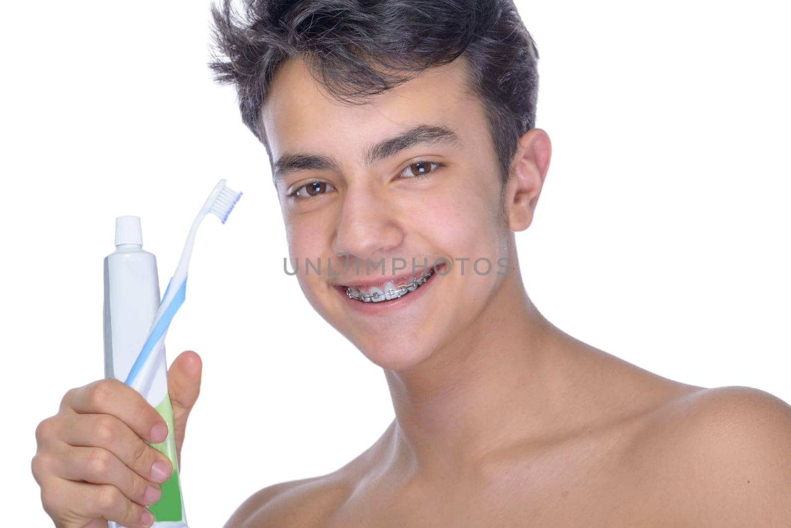 Cute teenager with white background, wearing braces on his teeth. Use toothbrush and toothbrush for cleaning.