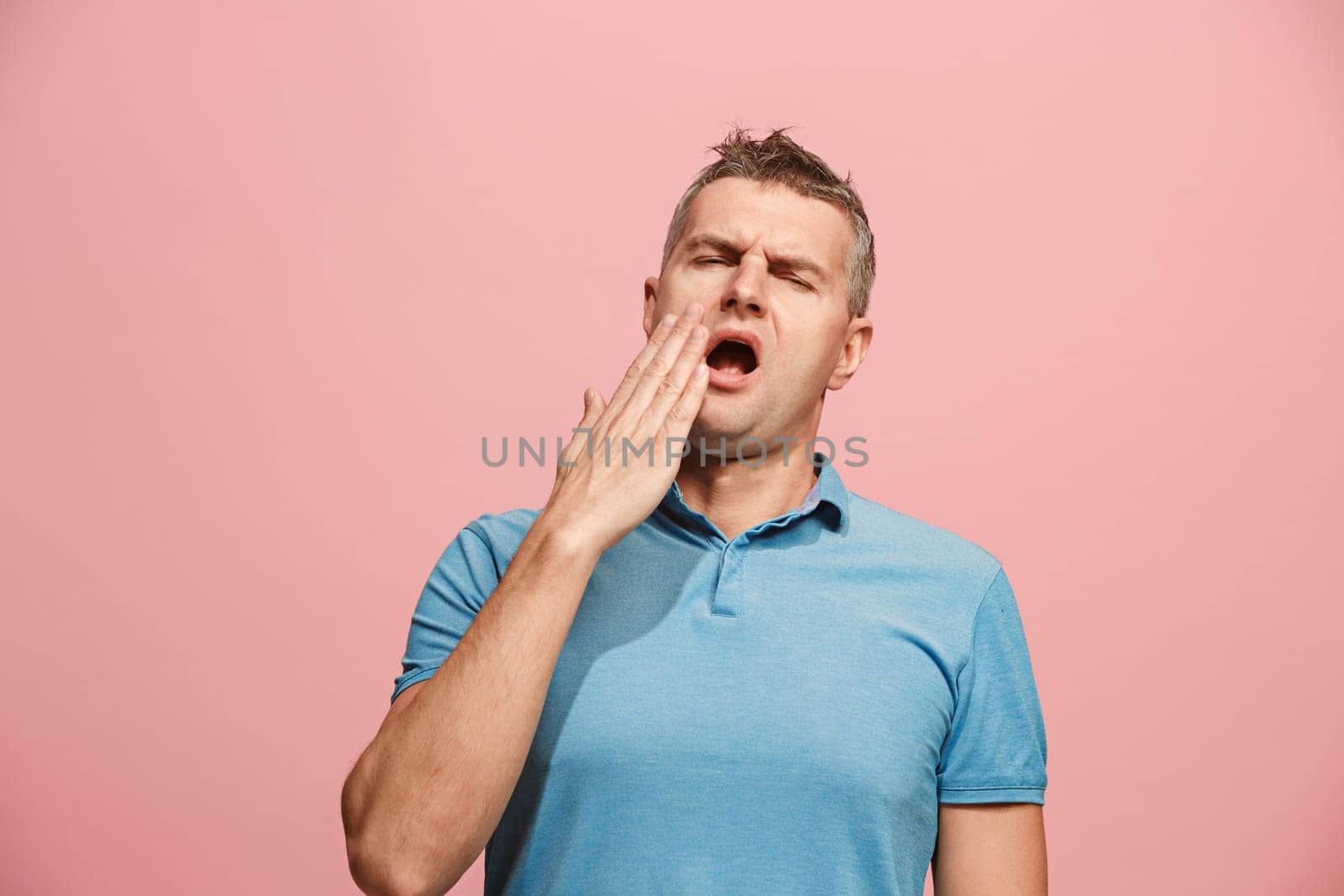 I am tired of everything. Bored man. Boring, dull, tedious concept. Young caucasian emotional man. Human emotions, facial expression concept. Studio Isolated on trendy pink background