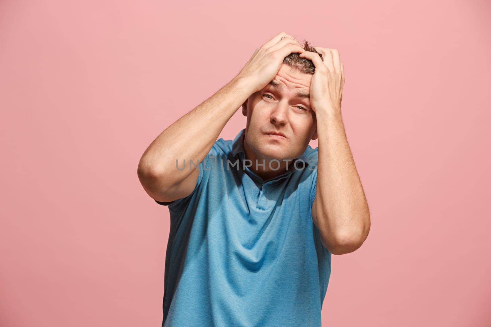 Horrible, stress, shock. Male half-length portrait isolated at pink studio. Young emotional surprised man clasping head in hands. Human emotions, facial expression concept. Trendy colors. Front view