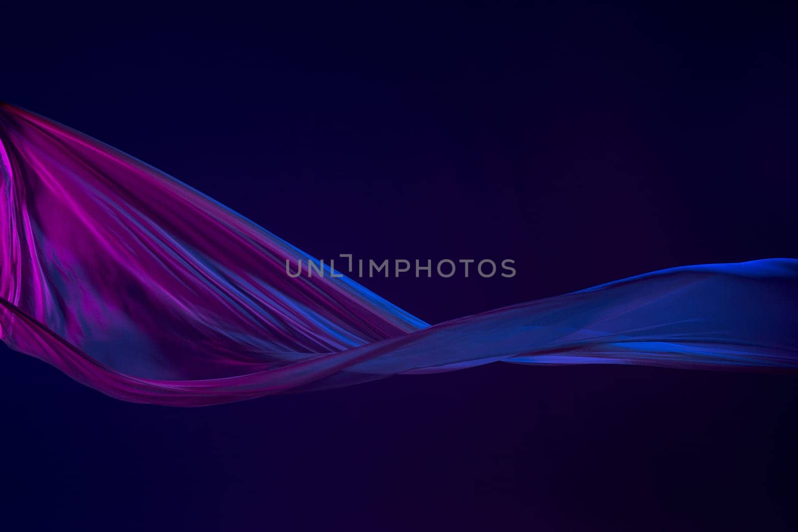 Smooth elegant transparent blue cloth isolated or separated on dark blue studio background. Texture of flying silk fabric.
