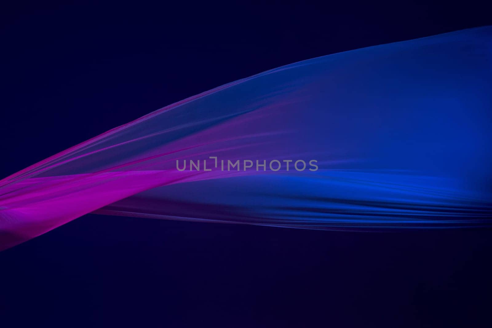Smooth elegant transparent blue cloth isolated or separated on dark blue studio background. Texture of flying silk fabric.