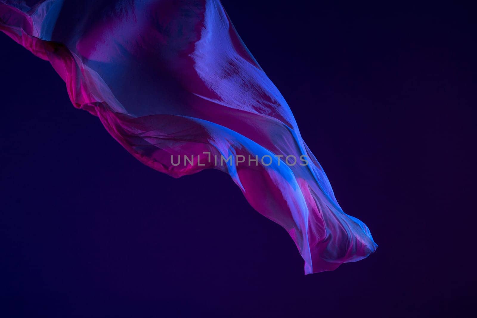 Smooth elegant transparent blue cloth isolated or separated on dark blue studio background. Texture of flying silk fabric.