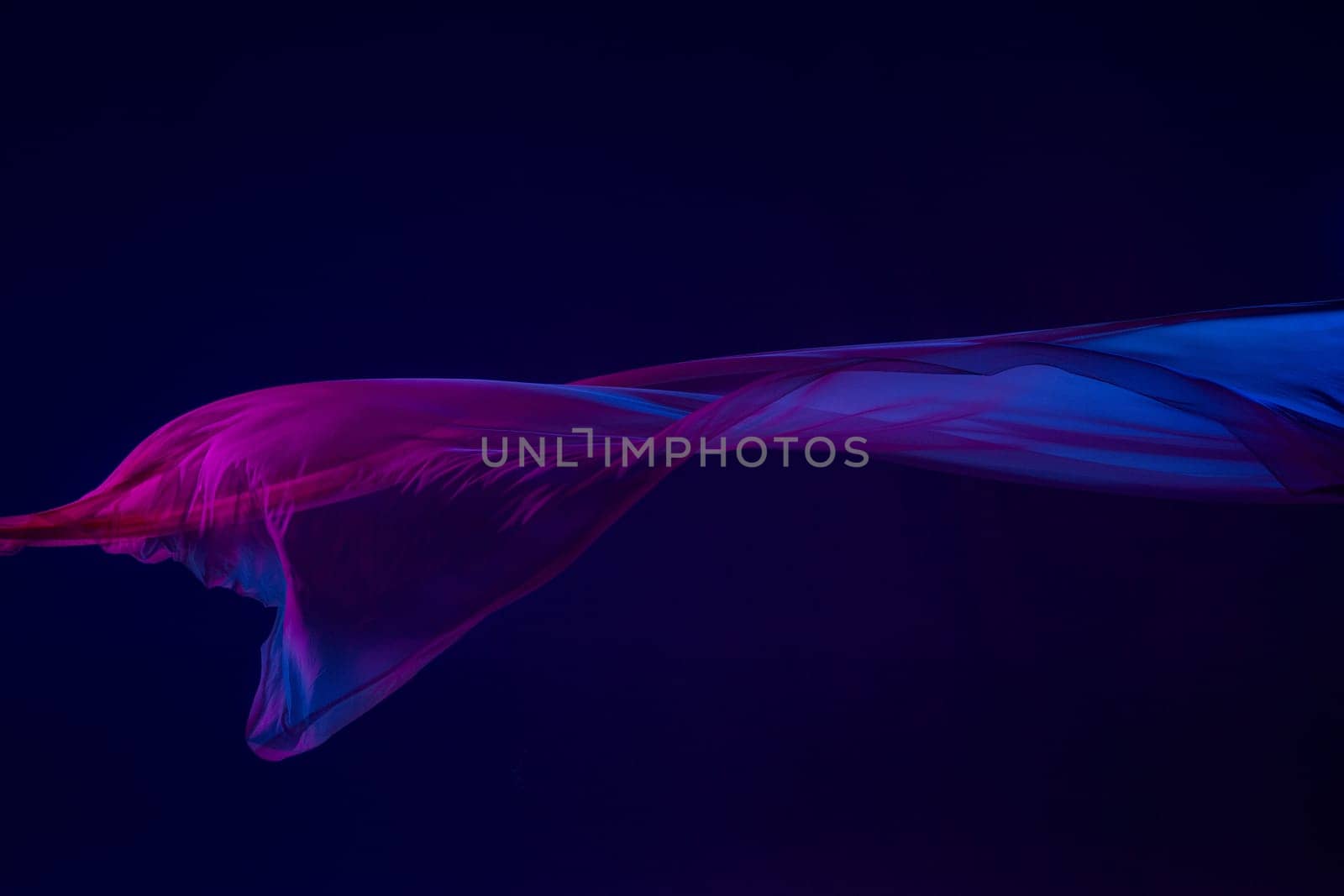 Smooth elegant transparent blue cloth isolated or separated on dark blue studio background. Texture of flying silk fabric.
