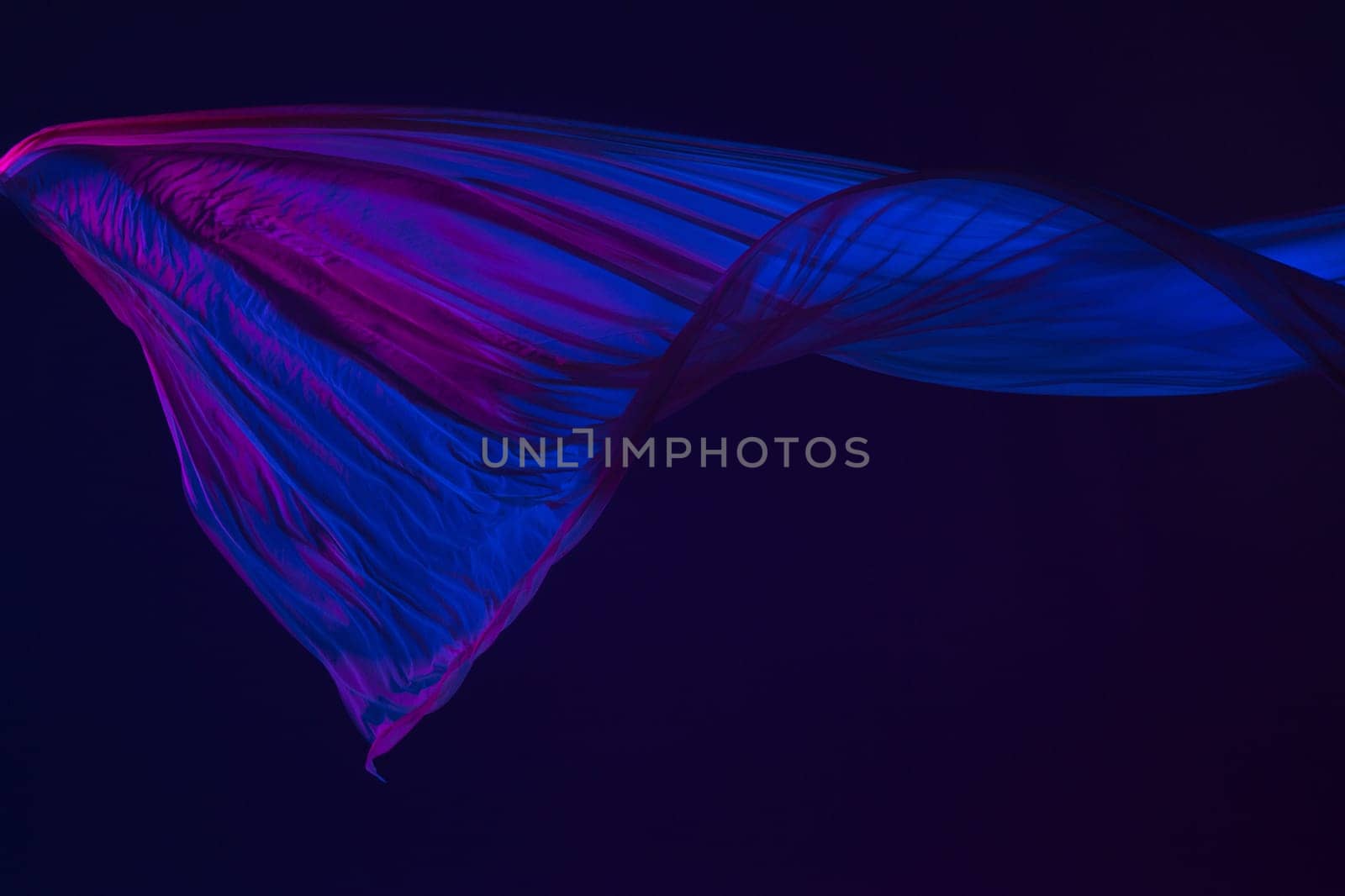 Smooth elegant transparent blue cloth isolated or separated on dark blue studio background. Texture of flying silk fabric.