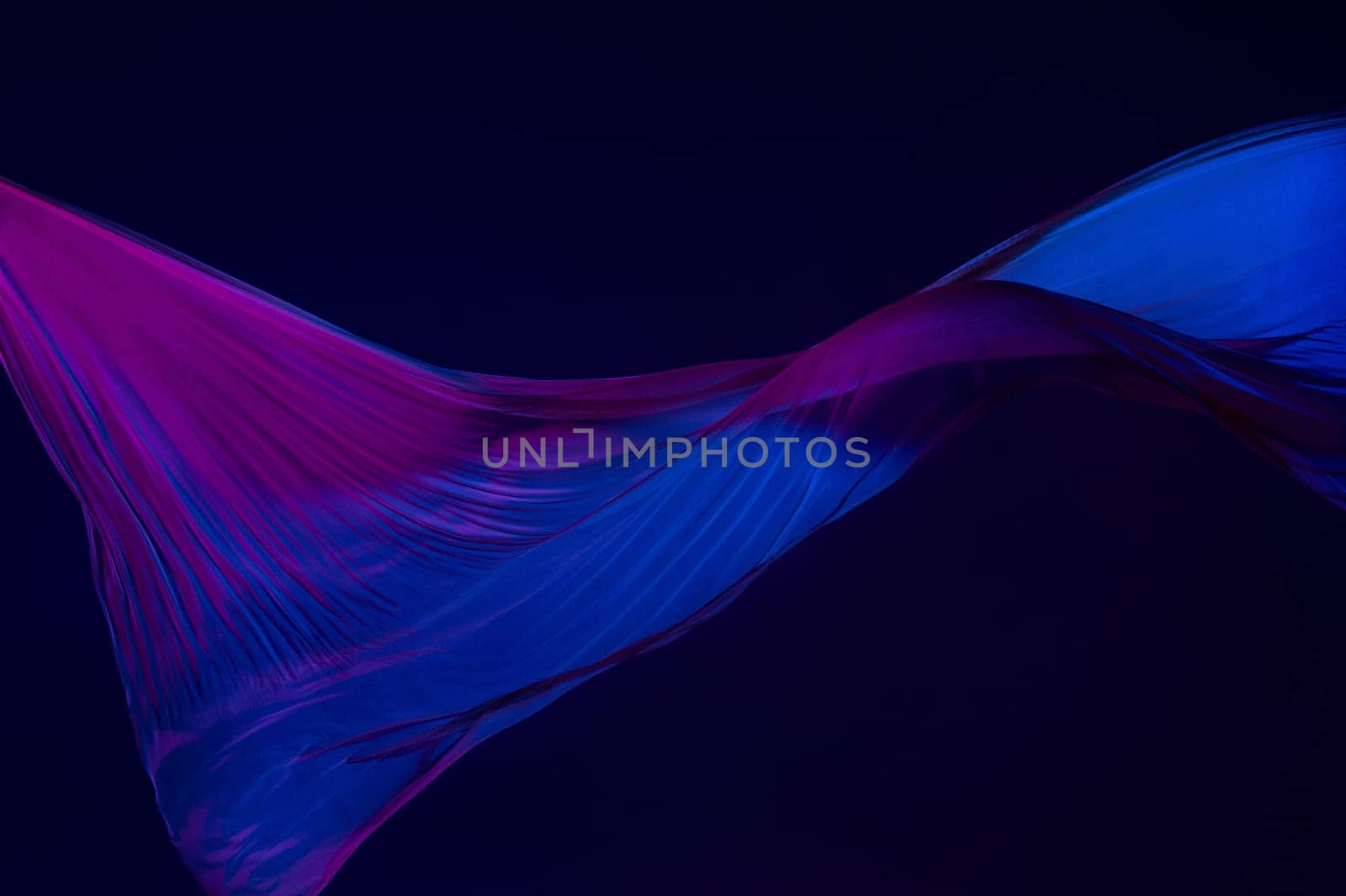 Smooth elegant transparent blue cloth isolated or separated on dark blue studio background. Texture of flying silk fabric.