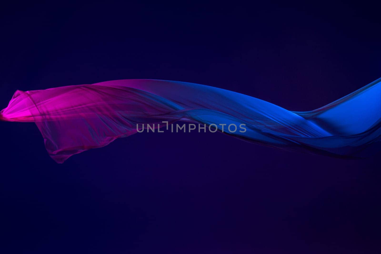 Smooth elegant transparent blue cloth isolated or separated on dark blue studio background. Texture of flying silk fabric.