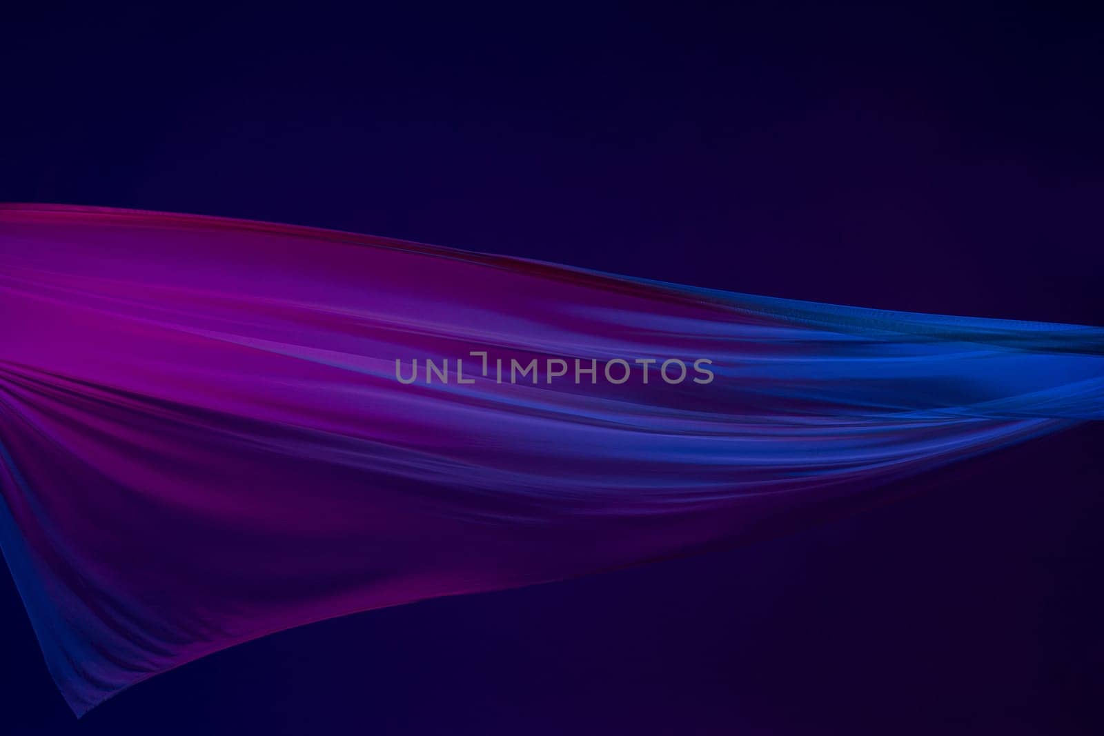 Smooth elegant transparent blue cloth isolated or separated on dark blue studio background. Texture of flying silk fabric.