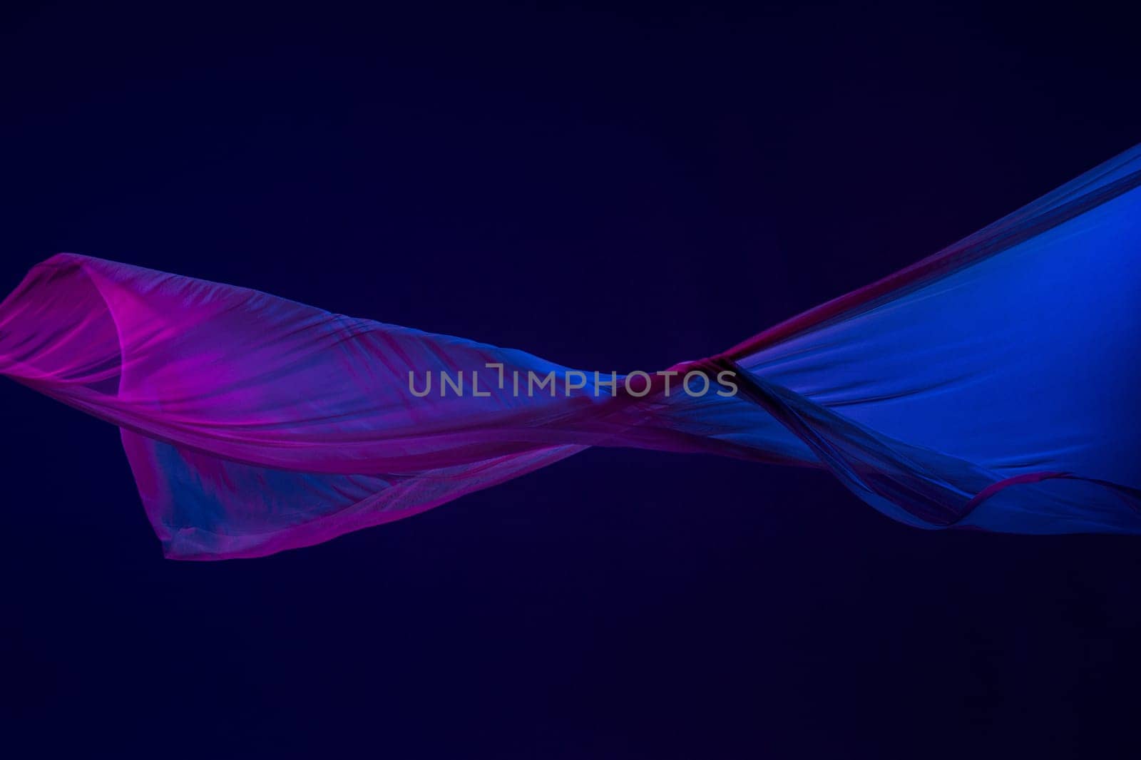 Smooth elegant transparent blue cloth isolated or separated on dark blue studio background. Texture of flying silk fabric.