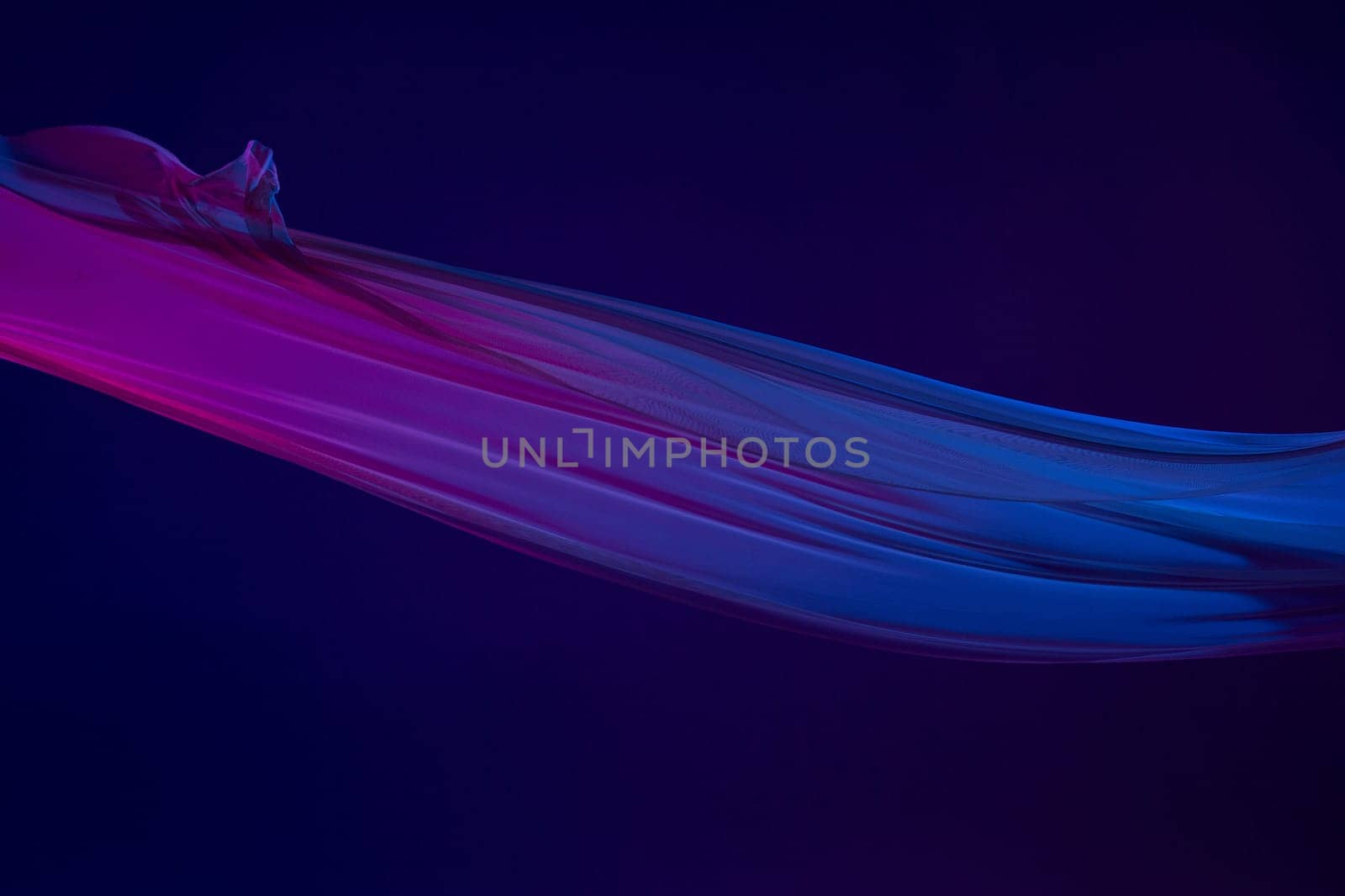 Smooth elegant transparent blue cloth isolated or separated on dark blue studio background. Texture of flying silk fabric.
