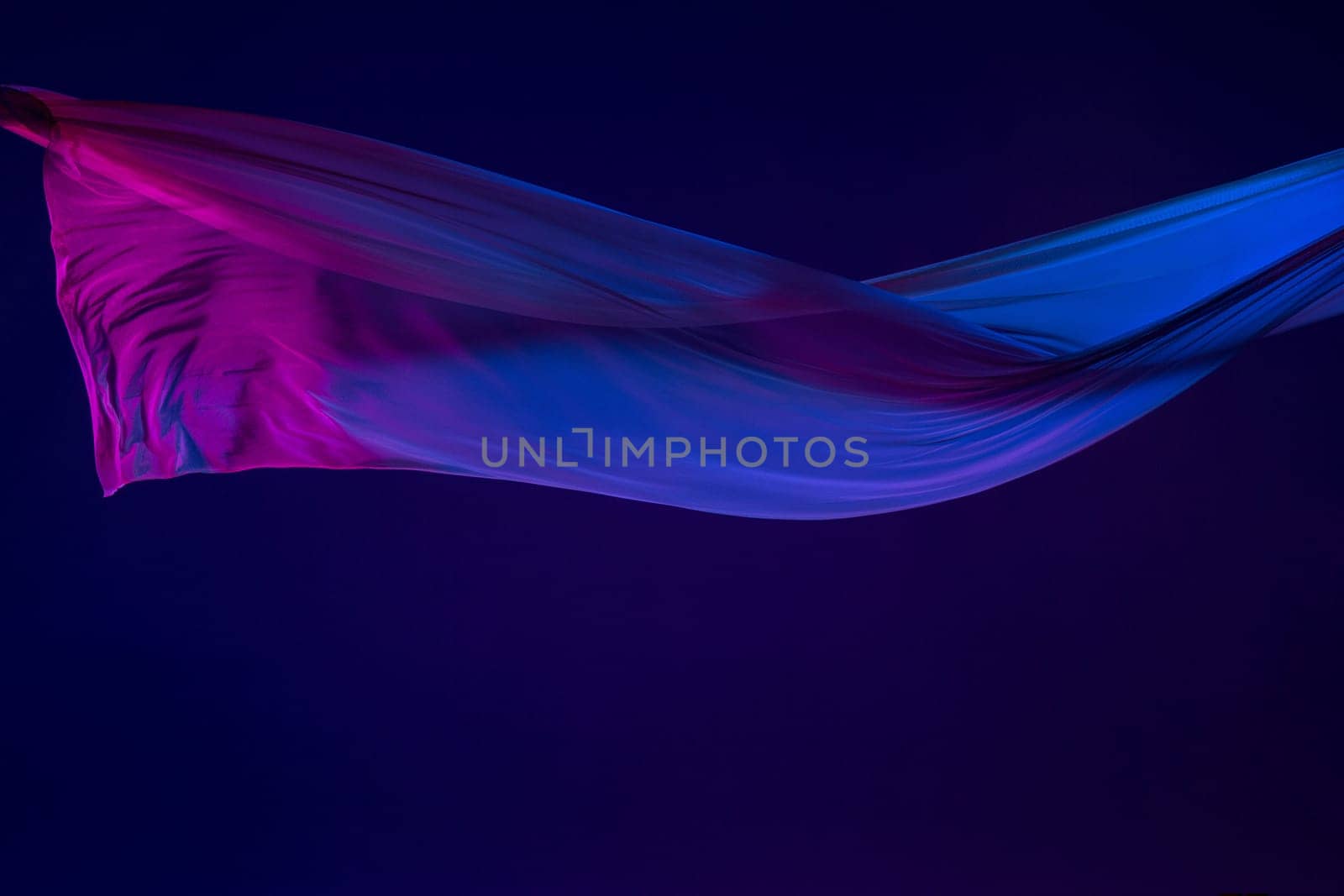 Smooth elegant transparent blue cloth isolated or separated on dark blue studio background. Texture of flying silk fabric.