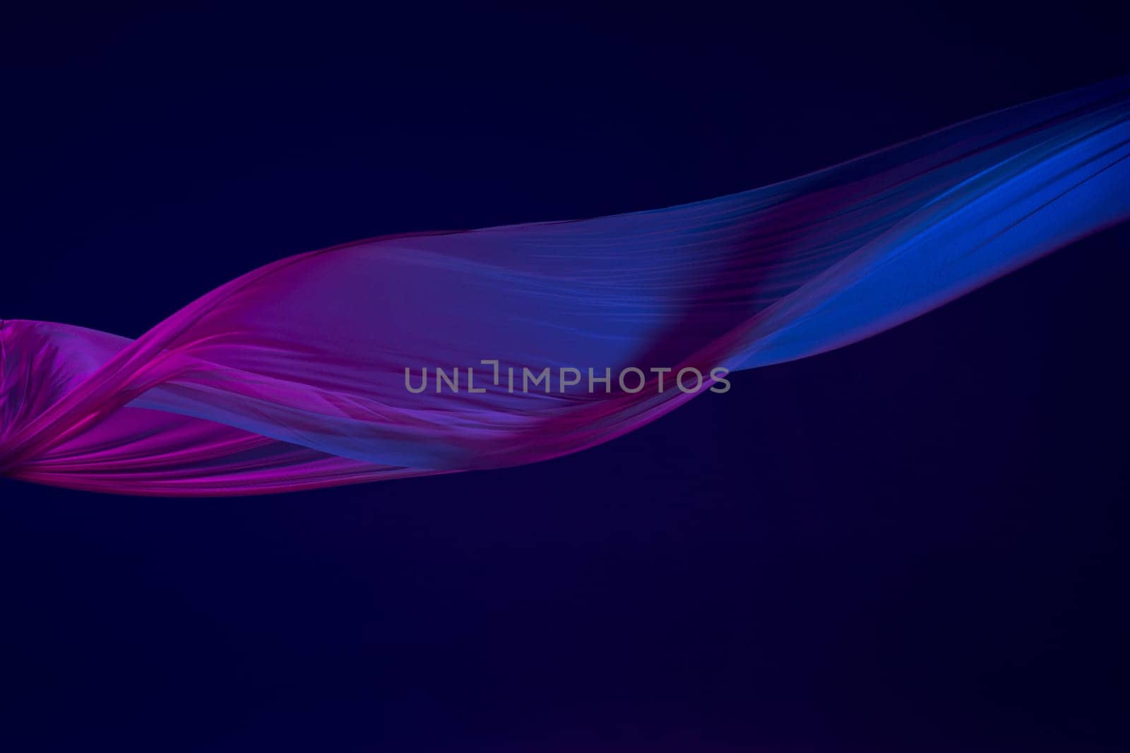 Smooth elegant transparent blue cloth isolated or separated on dark blue studio background. Texture of flying silk fabric.