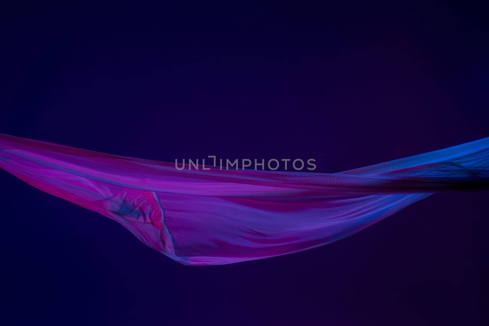 Smooth elegant transparent blue cloth isolated or separated on dark blue studio background. Texture of flying silk fabric.