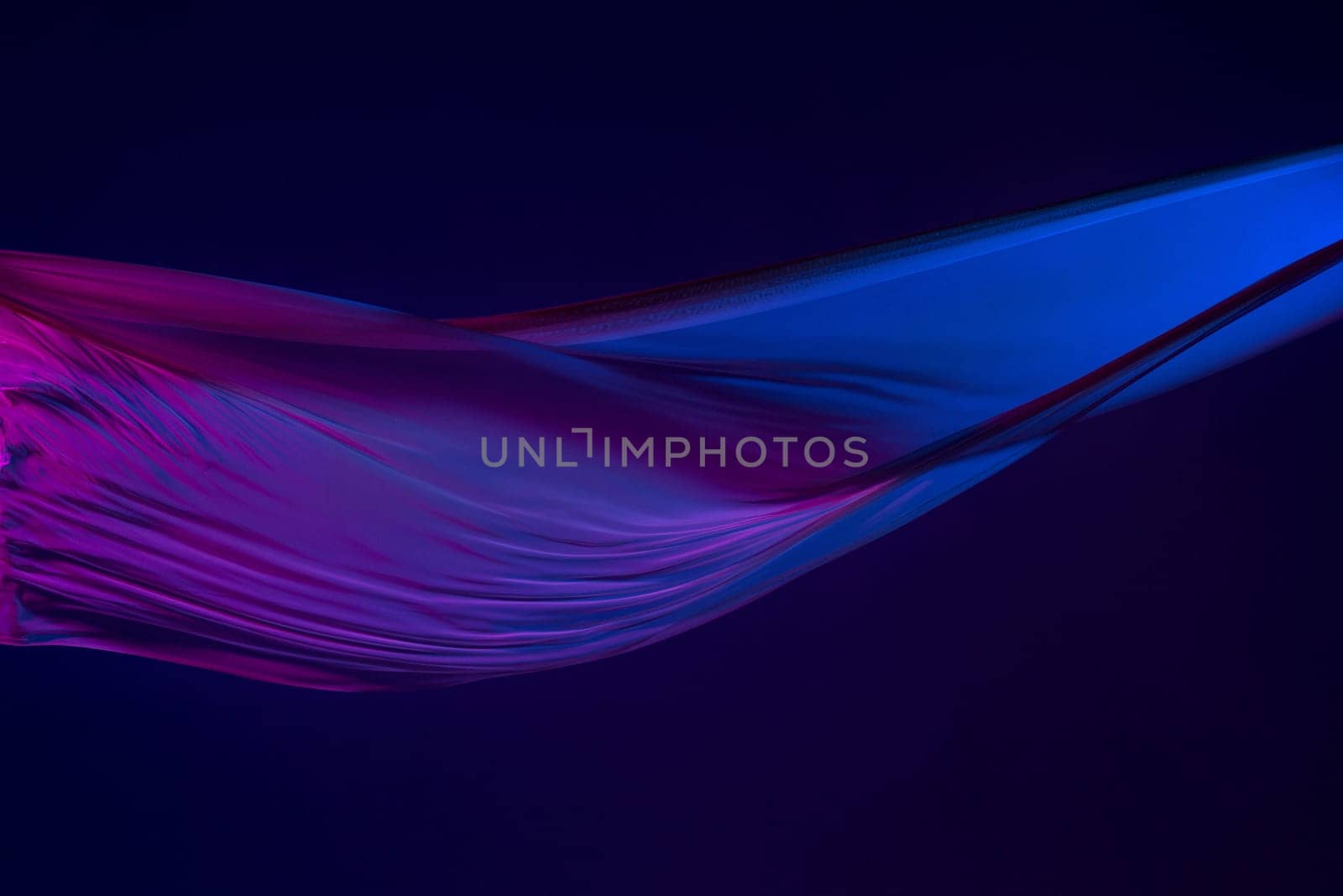 Smooth elegant transparent blue cloth isolated or separated on dark blue studio background. Texture of flying silk fabric.