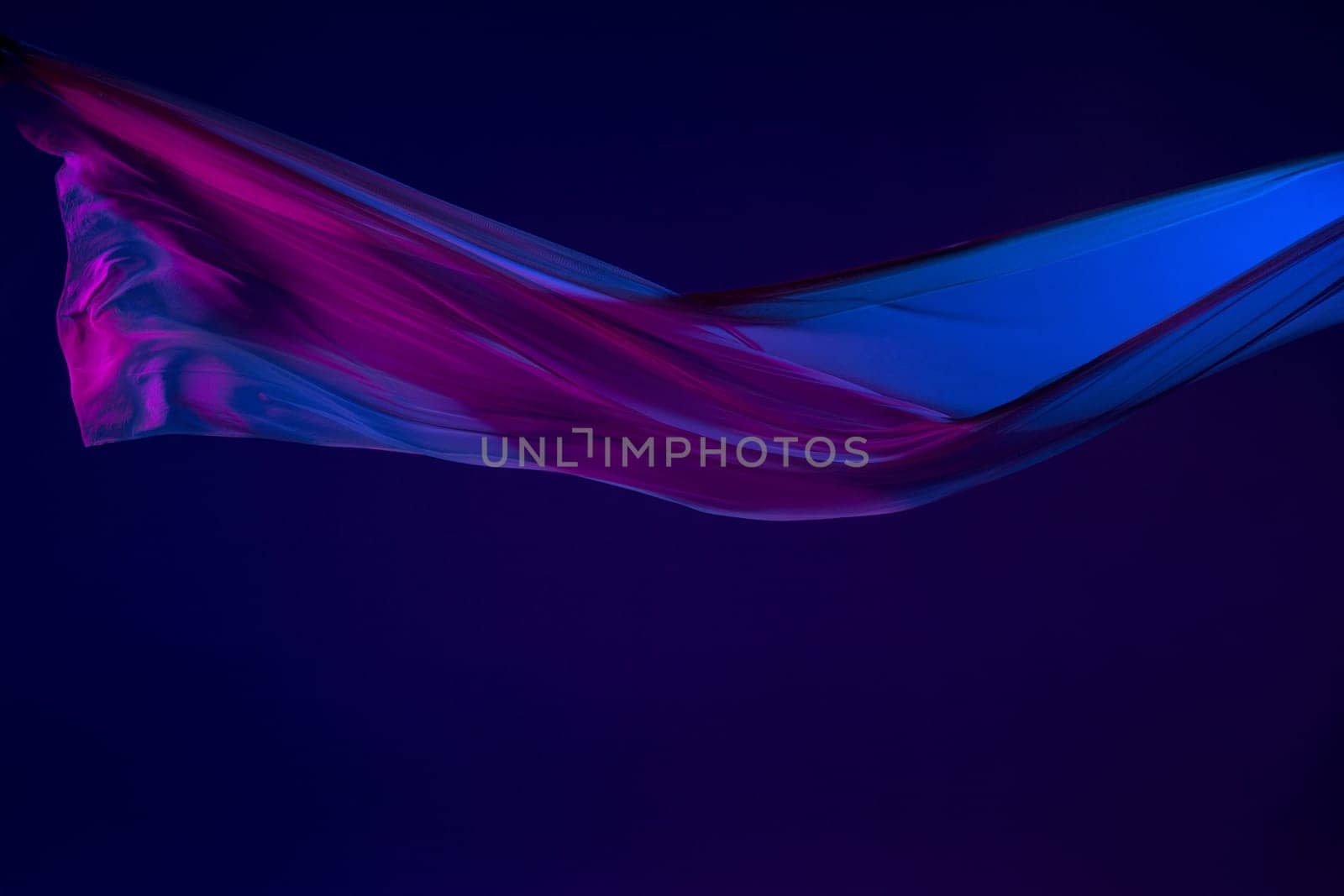 Smooth elegant transparent blue cloth isolated or separated on dark blue studio background. Texture of flying silk fabric.