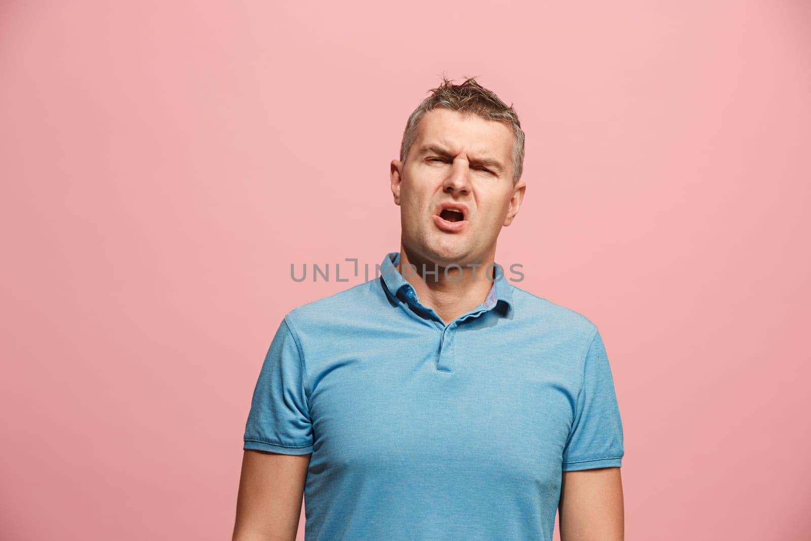 I am tired of everything. Bored man. Boring, dull, tedious concept. Young caucasian emotional man. Human emotions, facial expression concept. Studio Isolated on trendy pink background