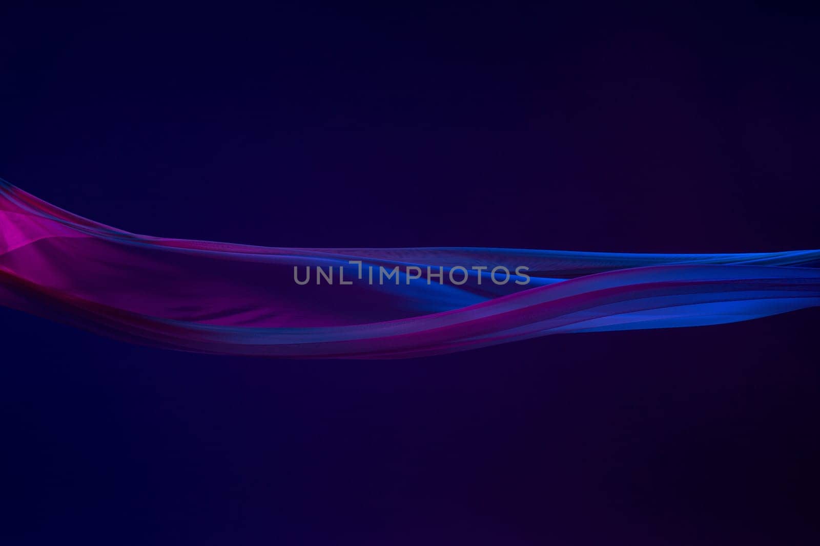 Smooth elegant transparent blue cloth isolated or separated on dark blue studio background. Texture of flying silk fabric.