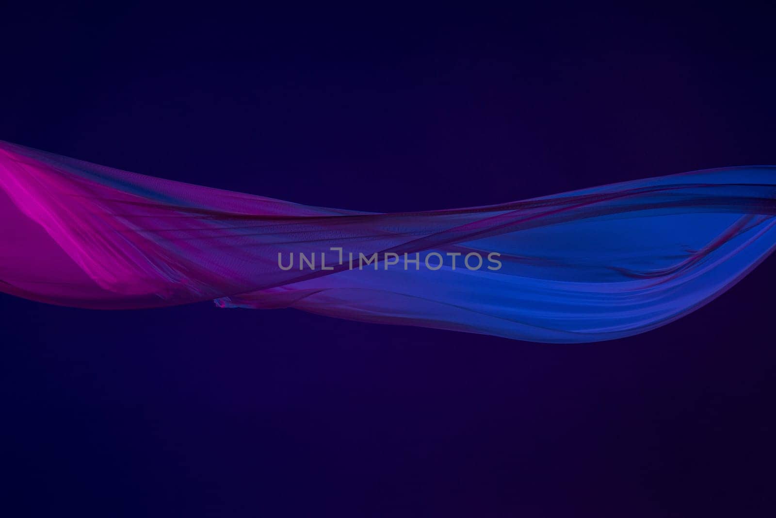 Smooth elegant transparent blue cloth isolated or separated on dark blue studio background. Texture of flying silk fabric.